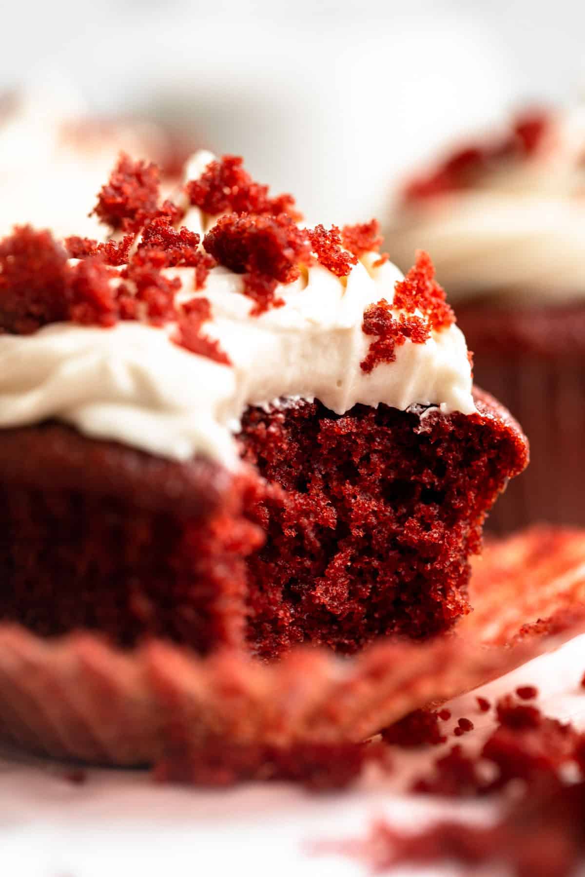 bite taken out of the gluten free red cupcake with the wrapper pulled off