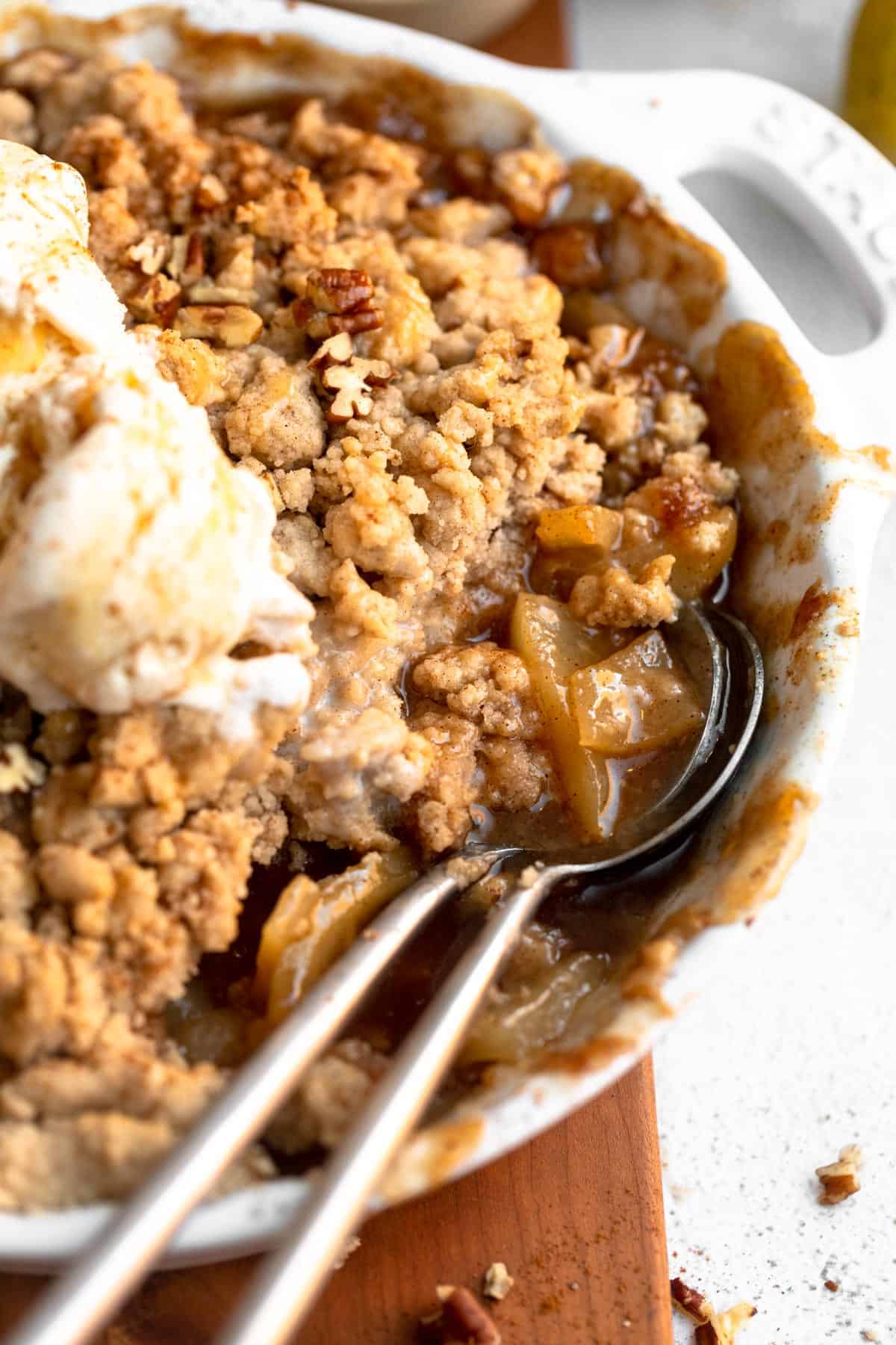 gluten free pear crumble in a pie dish with two spoons