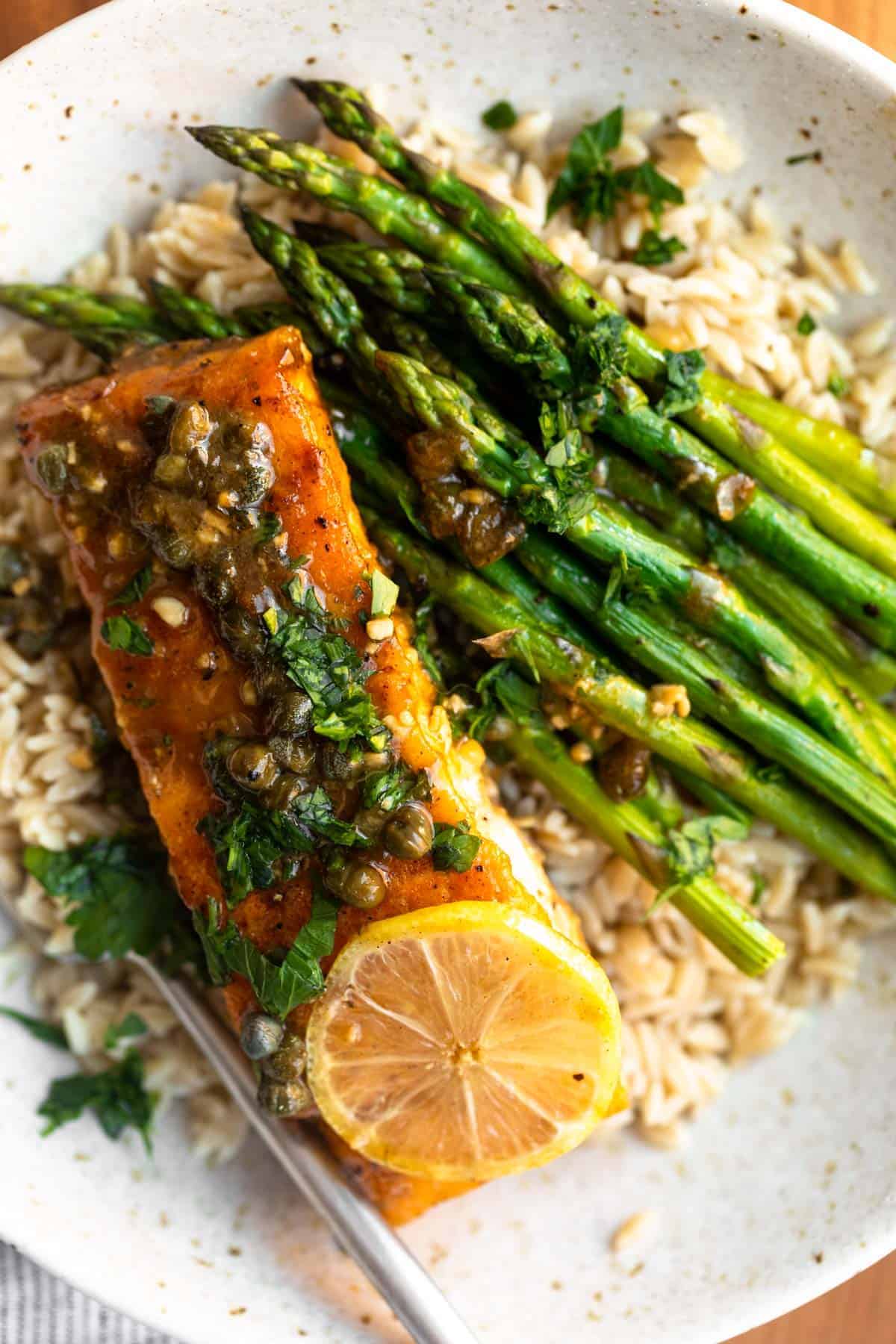 salmon piccata in a bowl with veggies on the side