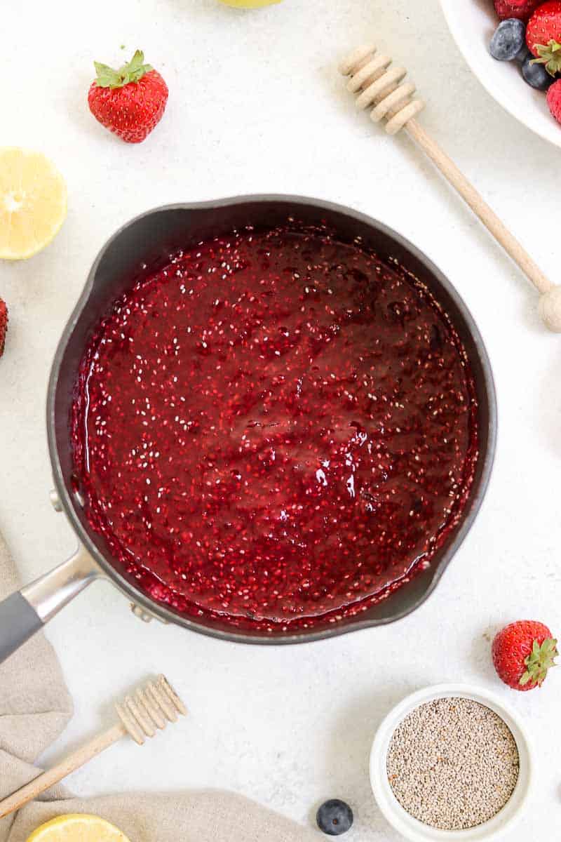 Chia jam in a black pot with fresh berries. 