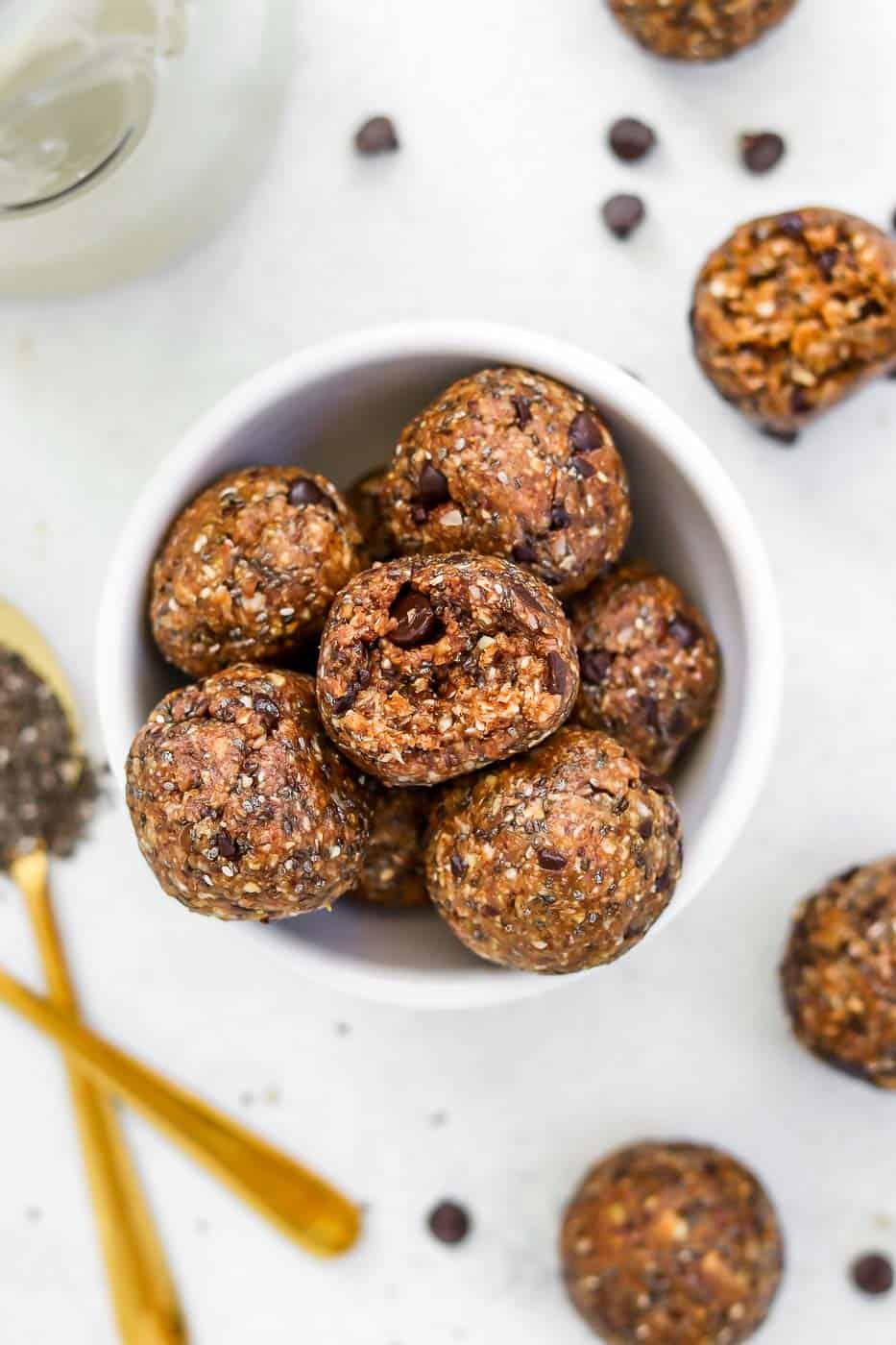 almond butter Energy balls in a white bowl with chocolate chips. 