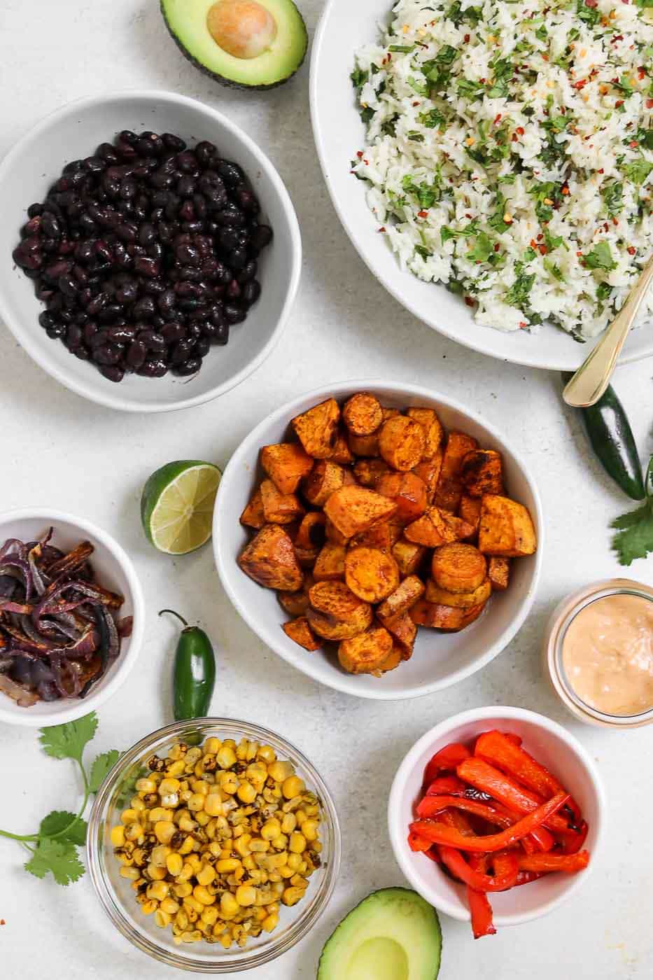 Ingredients for the vegan burrito bowl recipe in white bowls. 