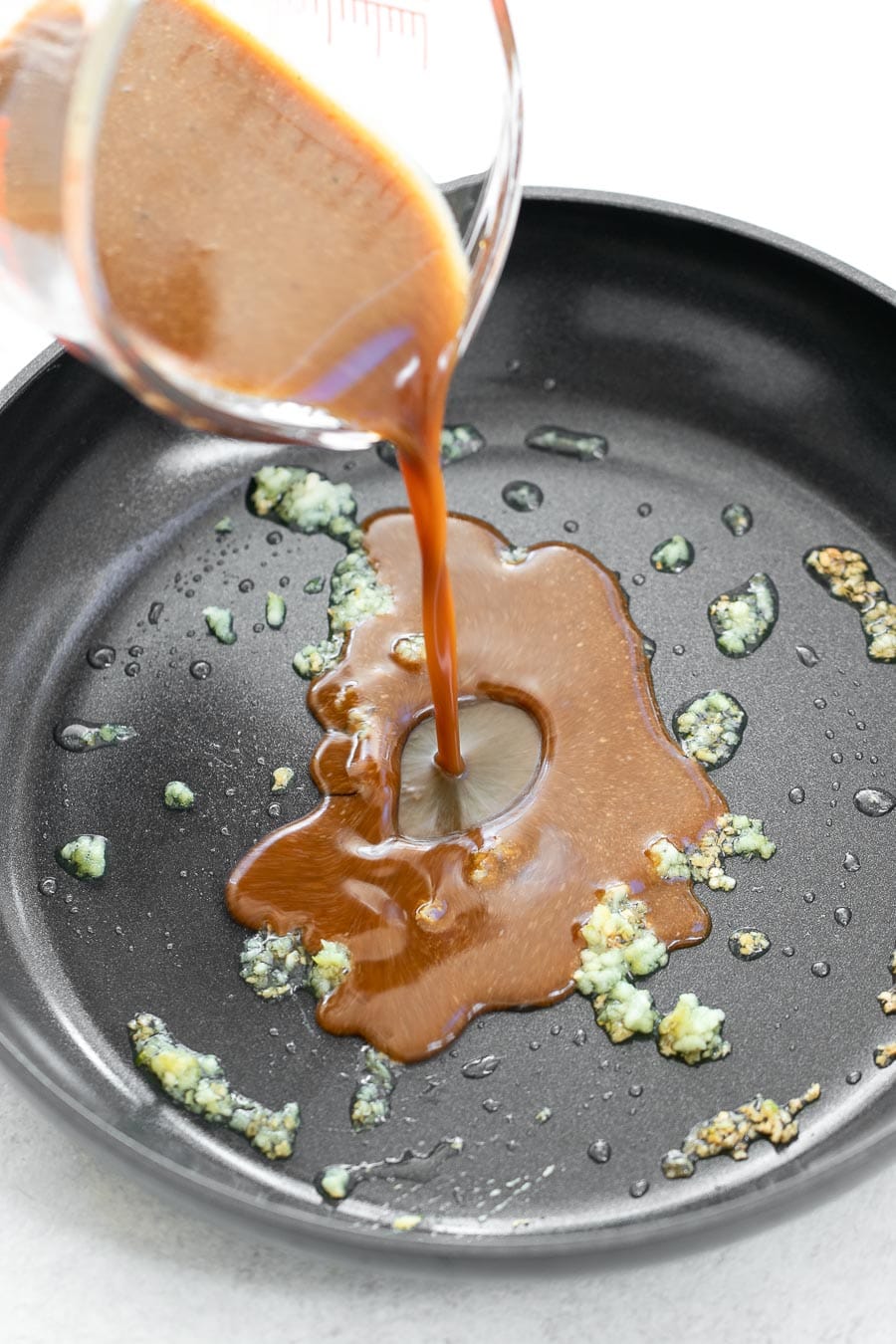 Pouring the sesame sauce into a pan with garlic.