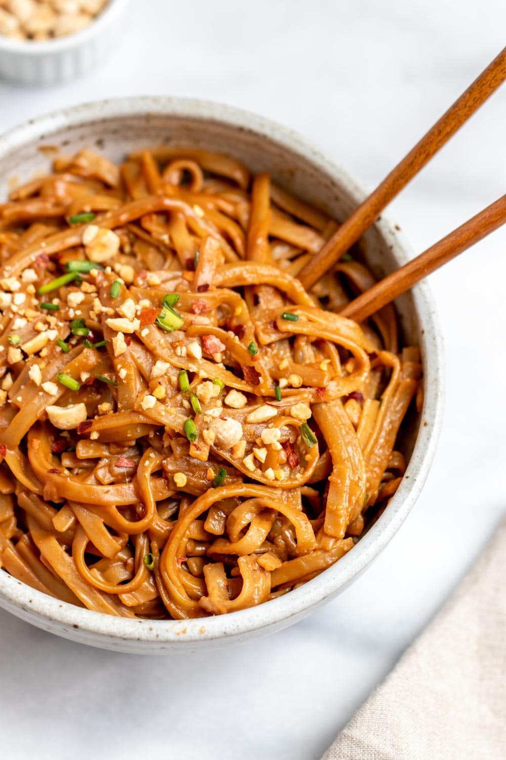 Peanut butter noodles with peanuts on top in a small bowl. 