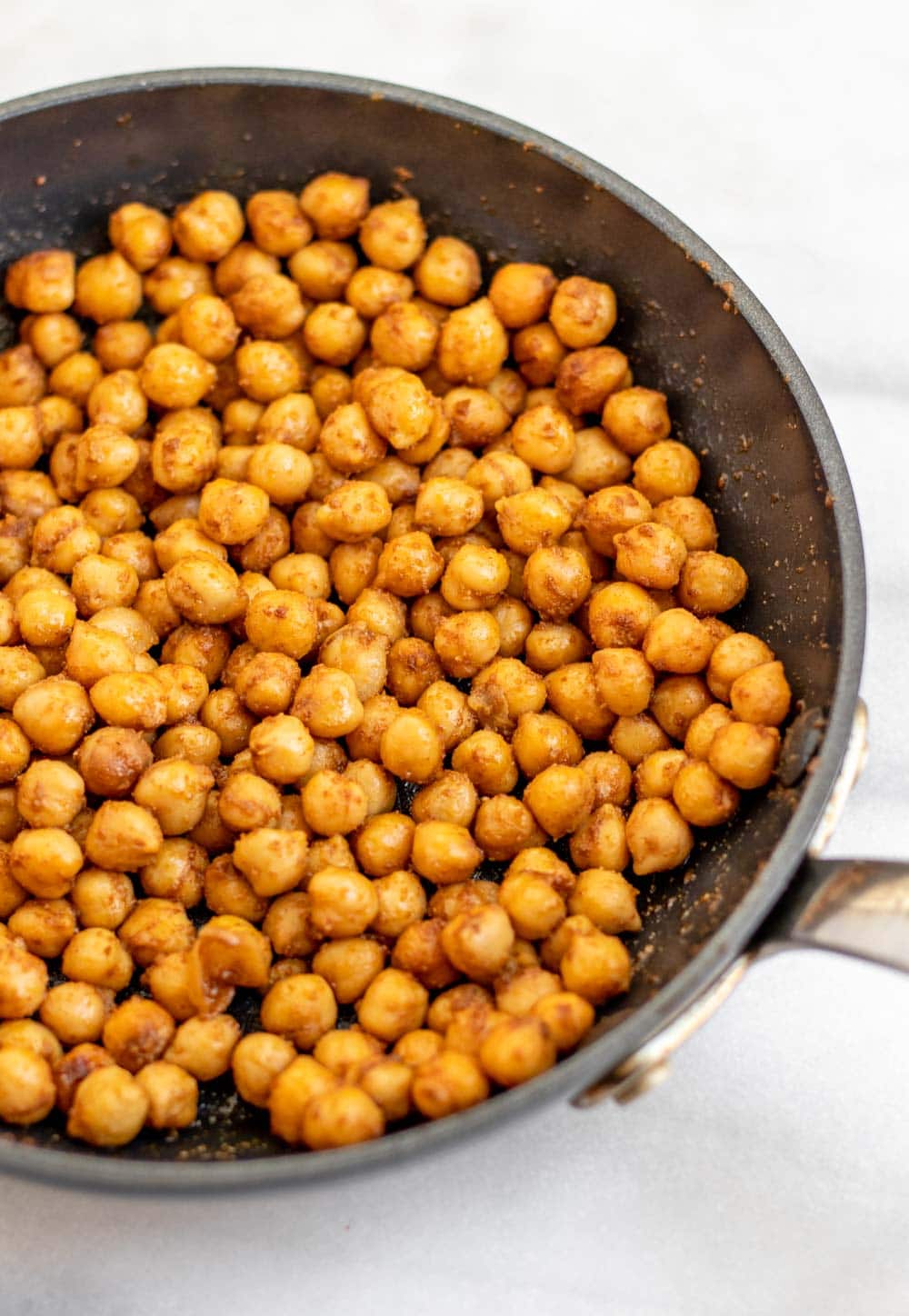Sauteed chickpeas in a large pan with seasonings.