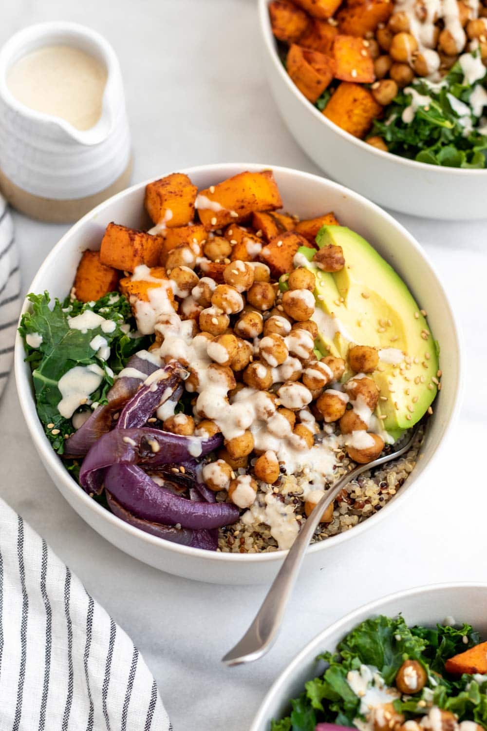 Sweet potato chickpea buddha bowl with dressing on top.
