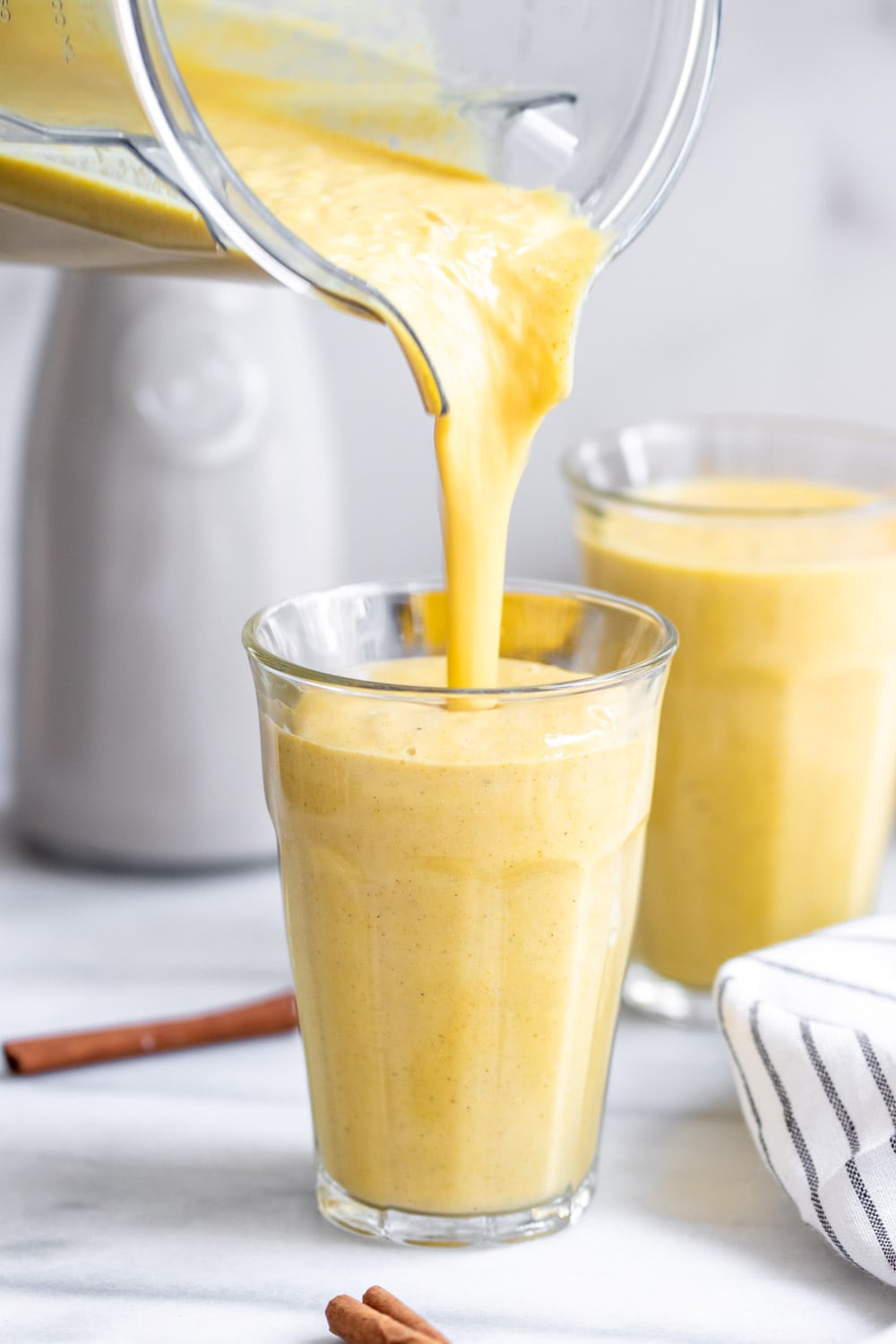 Pouring the golden milk smoothie into a glass cup. 