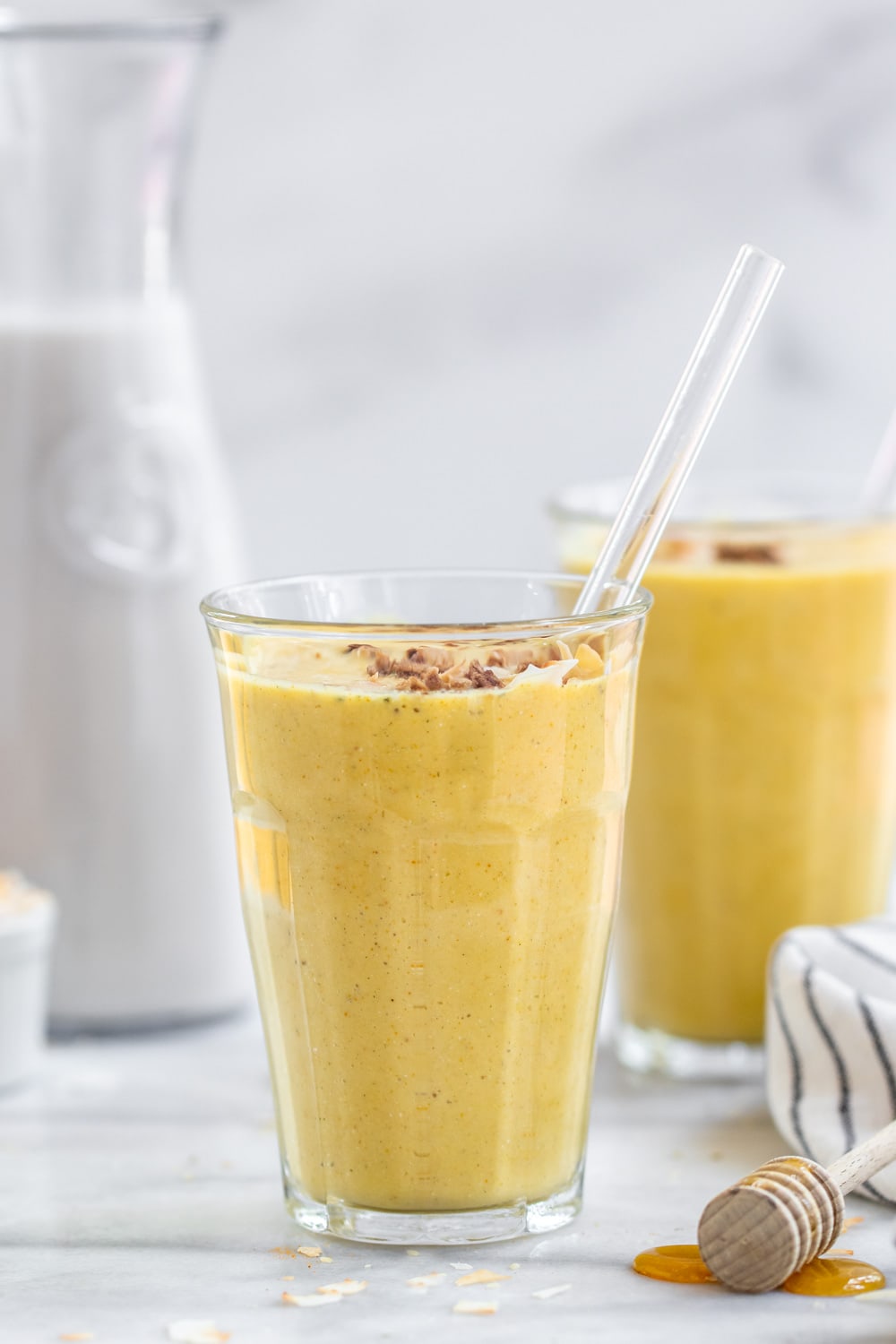 Golden milk smoothie in a glass cup with a straw.