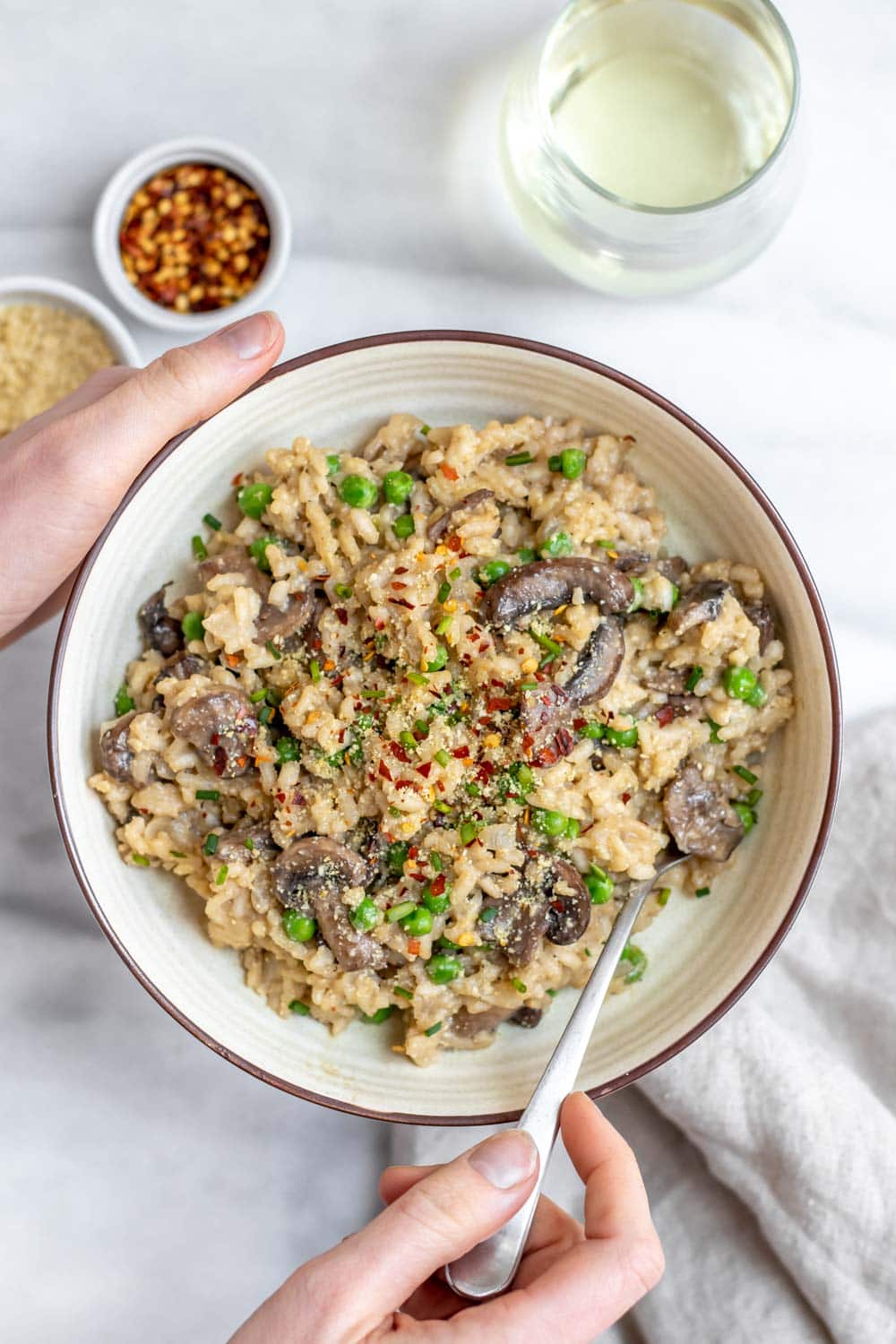 Vegan mushroom risotto in a bowl with hands holding it. 