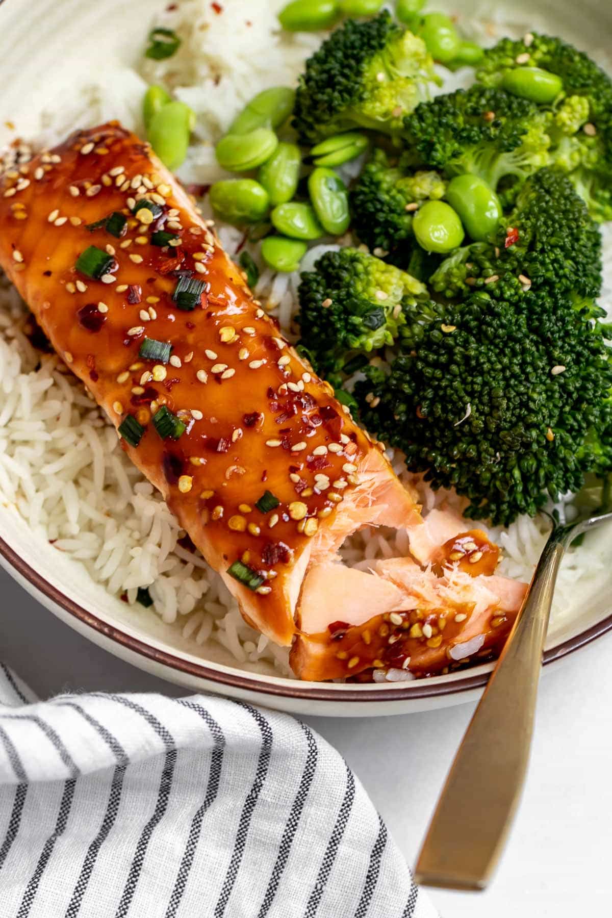 Baked teriyaki salmon over a bed of rice with one bite taken out.