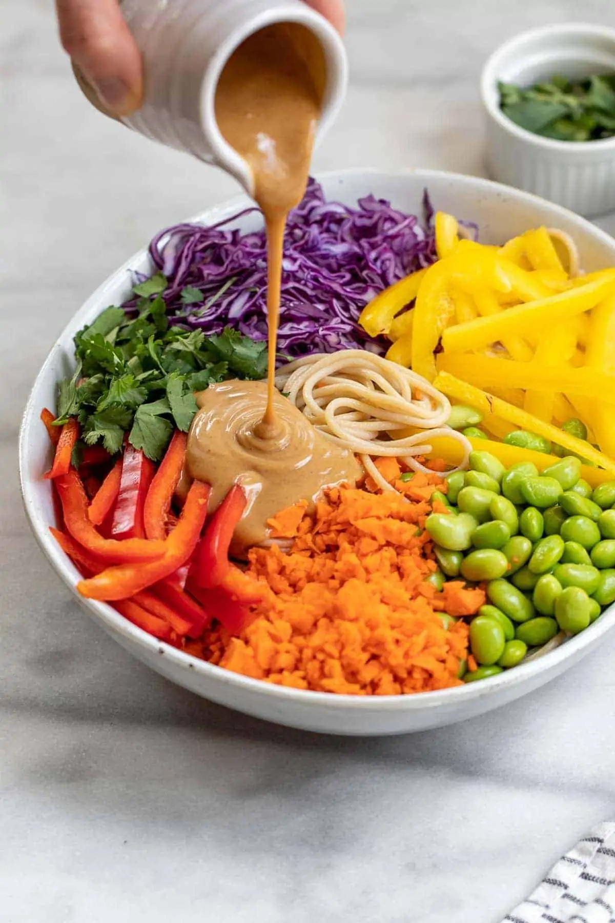 Pouring the thai peanut sauce over the noodles and veggies.