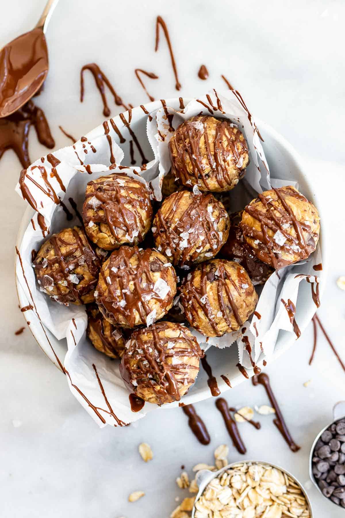 Peanut butter protein balls in a small bowl with chocolate drizzle on top.