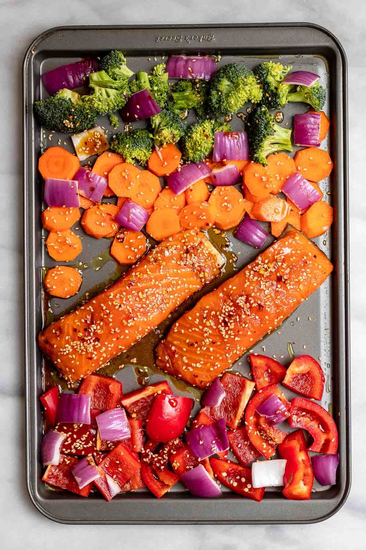 Salmon and veggies before going in the oven on a cookie sheet.