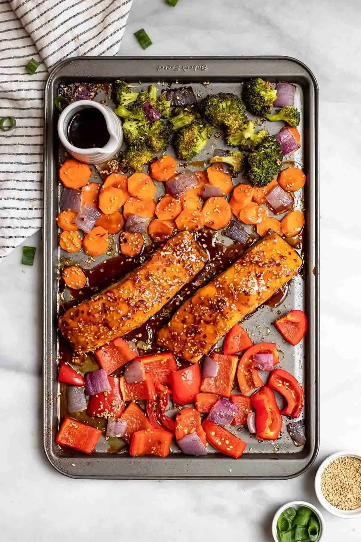 Overhead shot of sheet pan maple salmon with vegetables and sesame seeds.