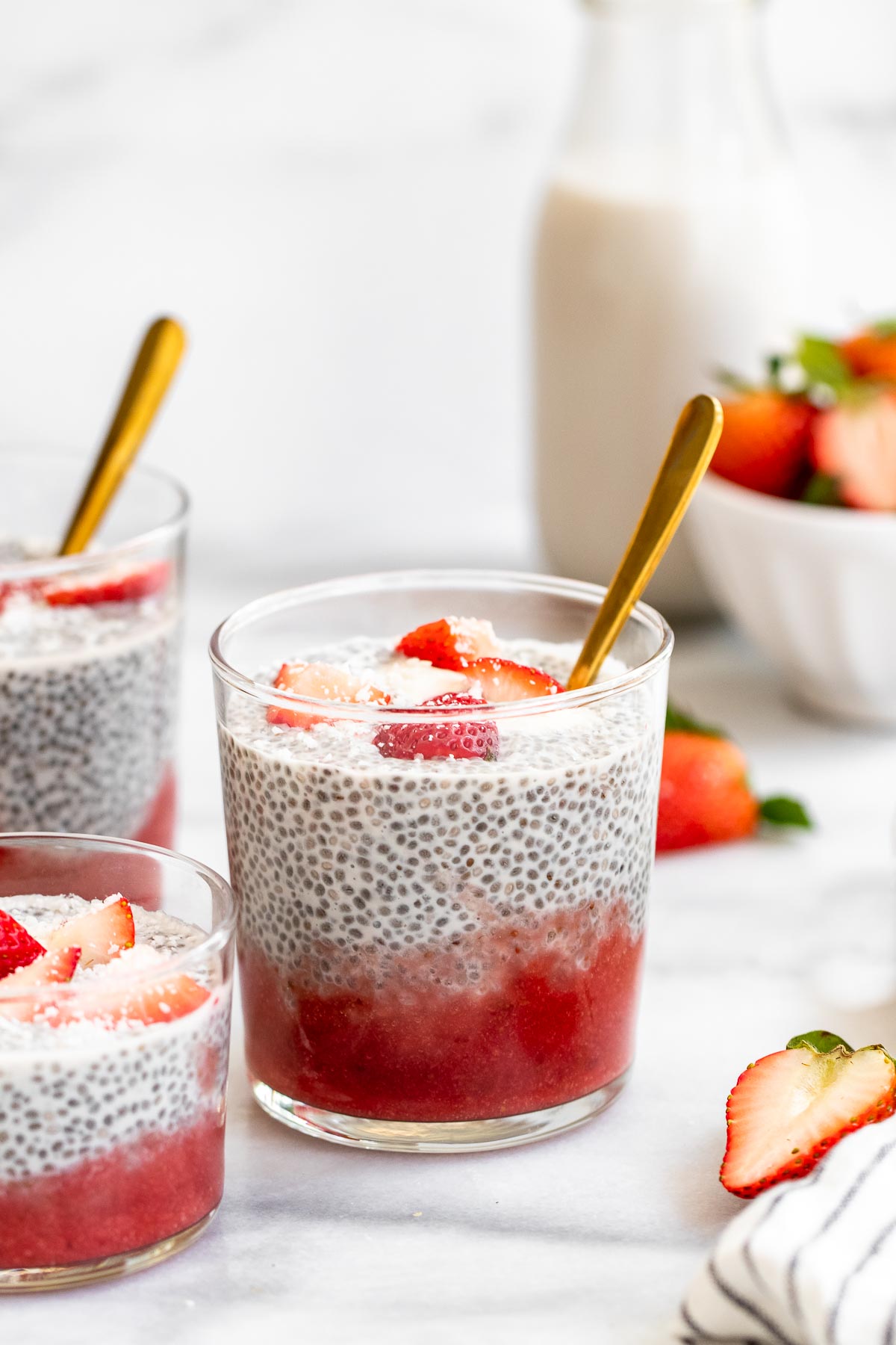 Chia pudding with a layer of strawberry puree on the bottom with a gold spoon on the side.