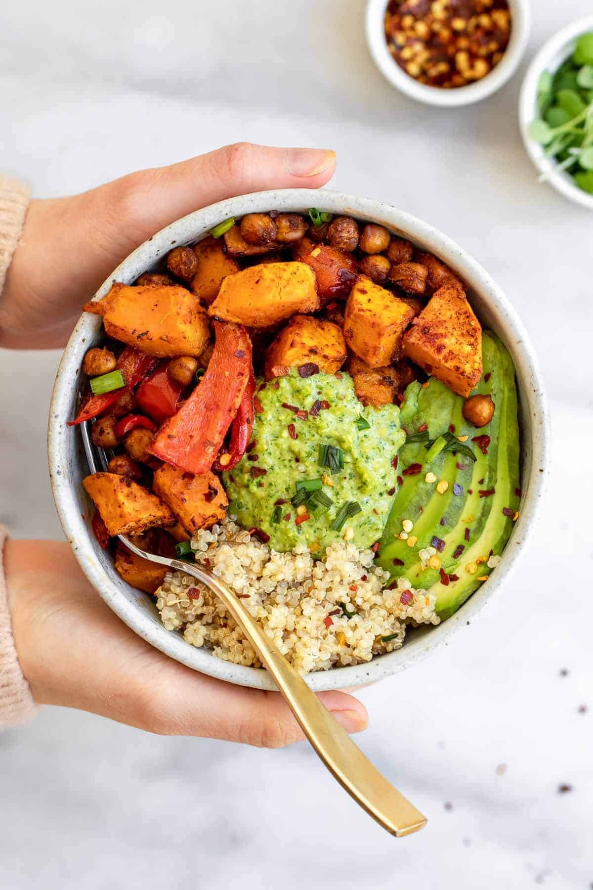 Two hands holding the bowl with the vegan sweet potato and chickpea recipe.