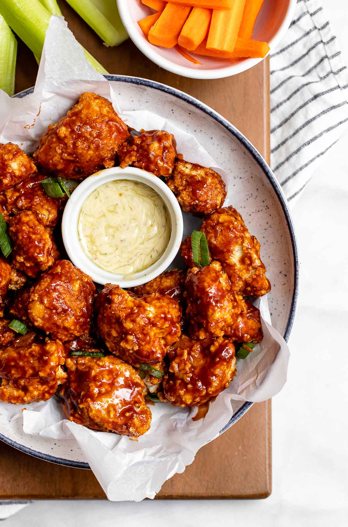 Overhead shot of bbq cauliflower wings with chopped scallions in a bowl.