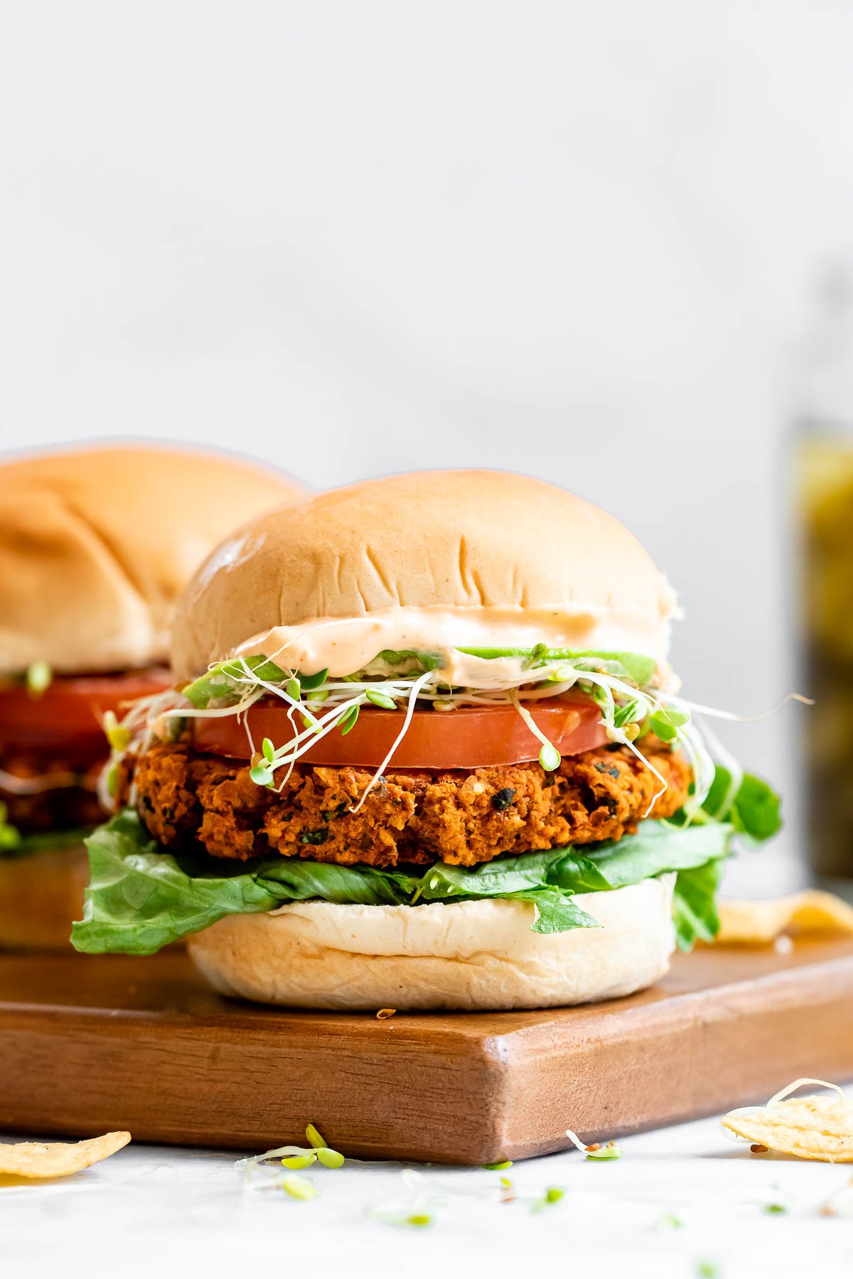 Two vegan chickpea burgers sitting on a wood board.