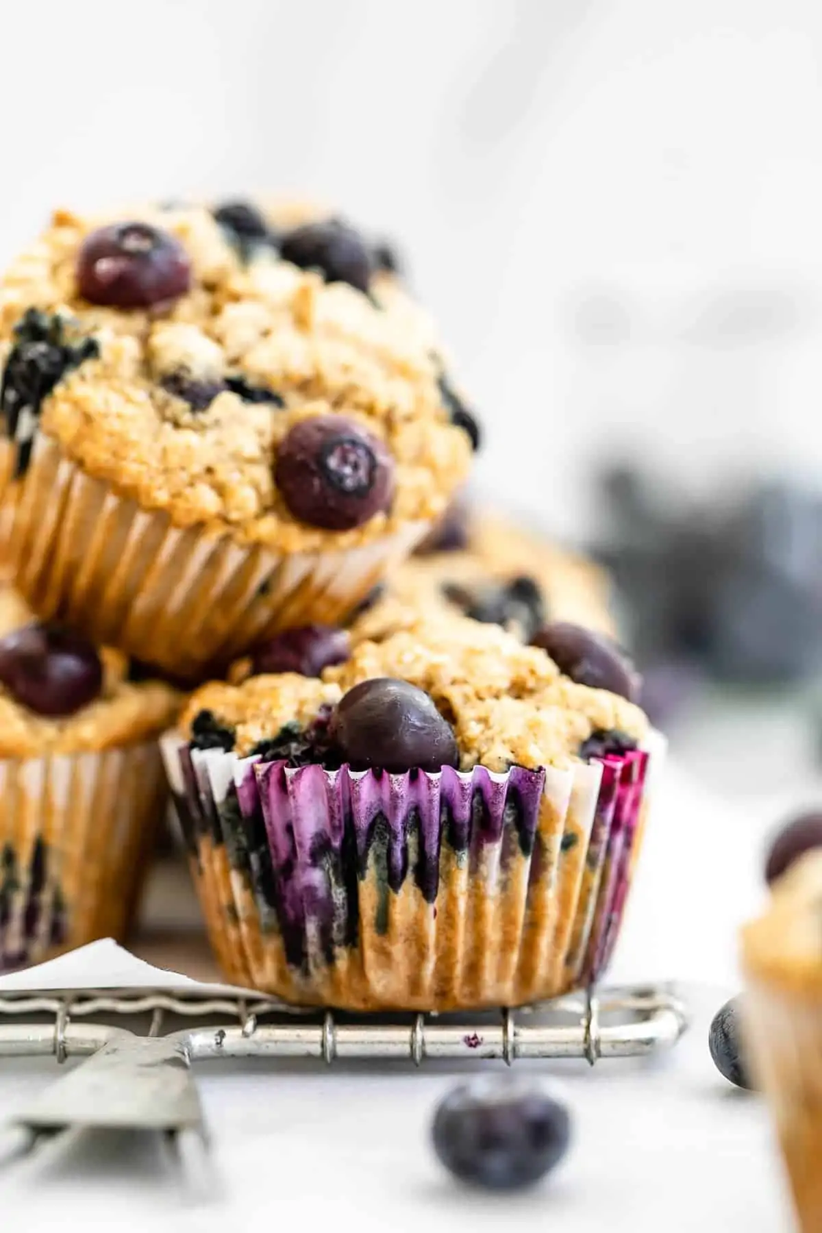Blueberry muffins stacked on top of each other on a wire rack.