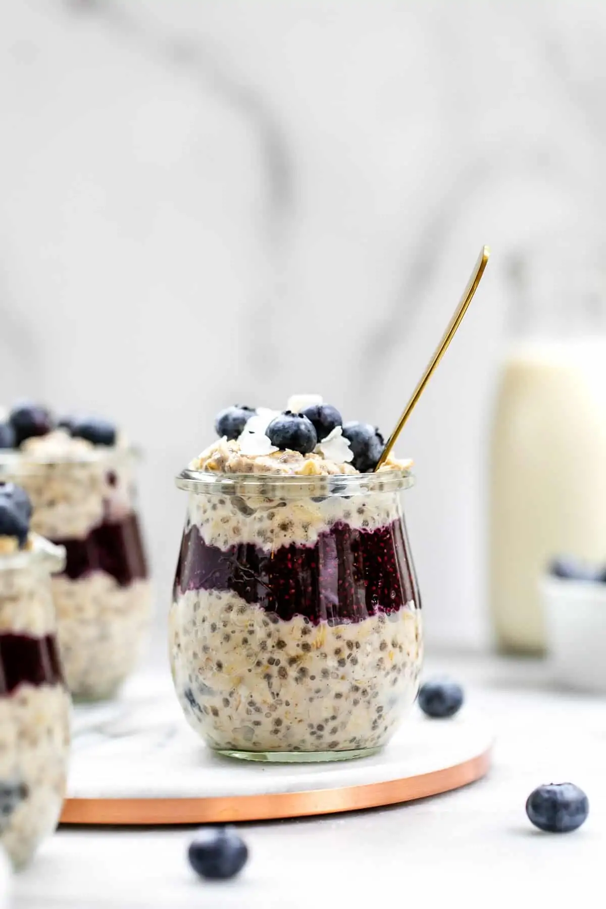 Blueberry overnight oats in a small glass jar with chia jam in the middle.