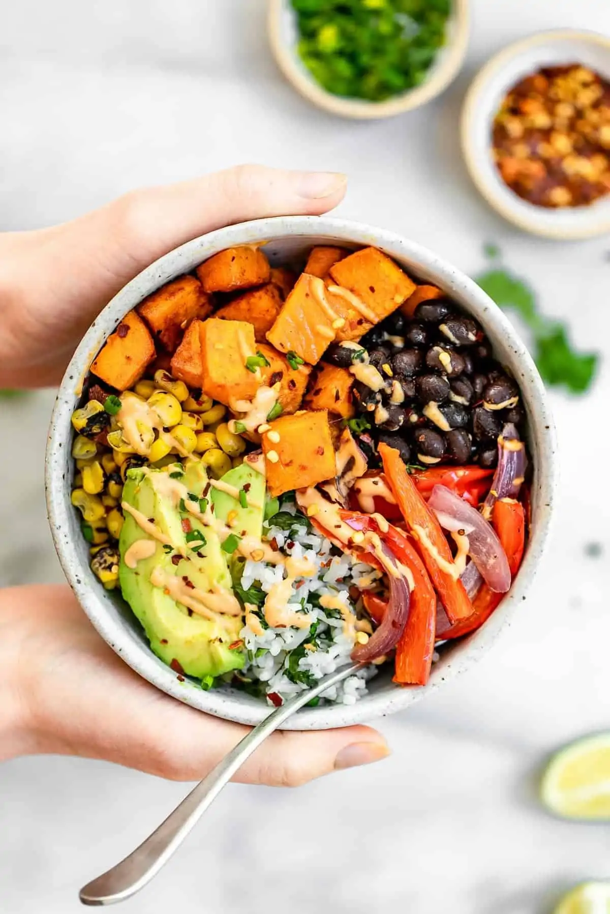Hand holding the burrito bowl with roasted veggies and sweet potato.