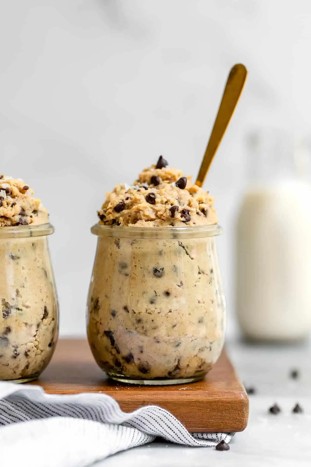 Two small glass jars with the chickpea cookie dough pouring out the top.