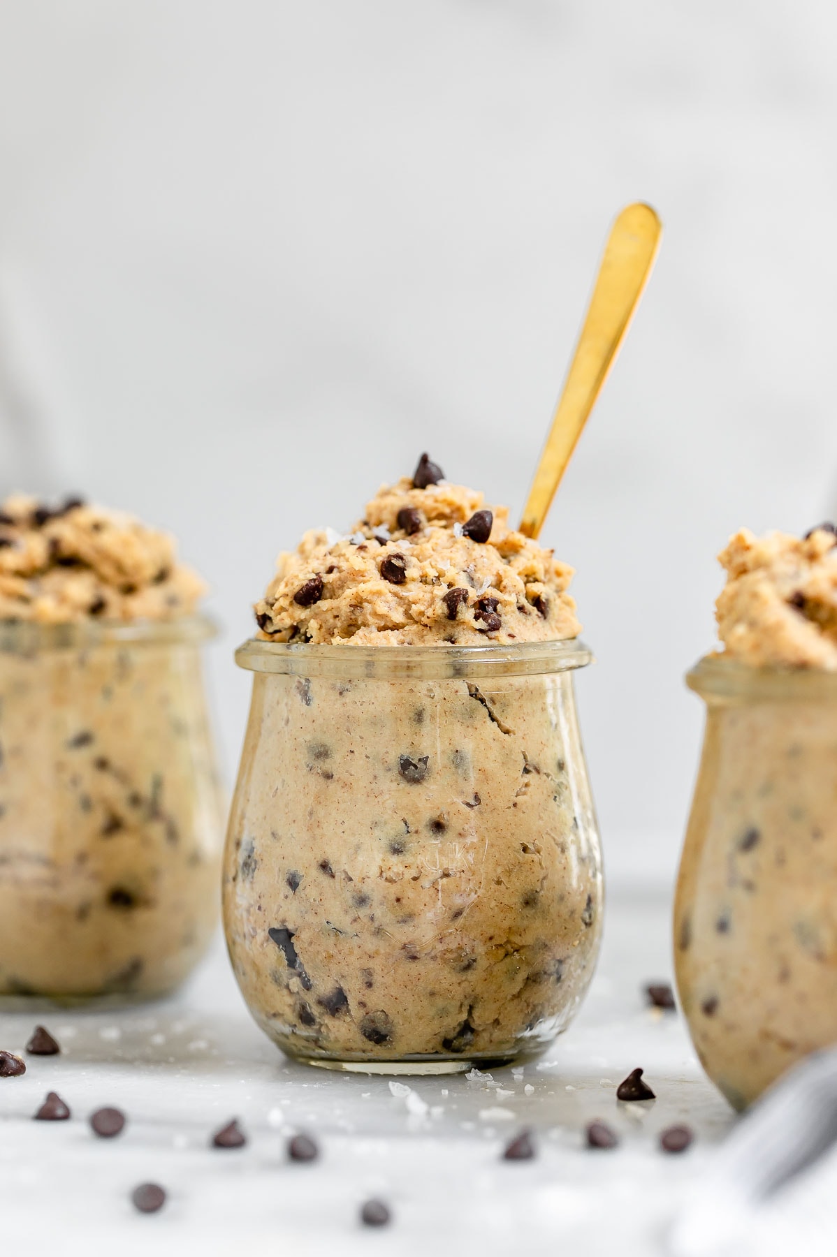 Vegan chickpea cookie dough in small glass jars with chocolate chips. 