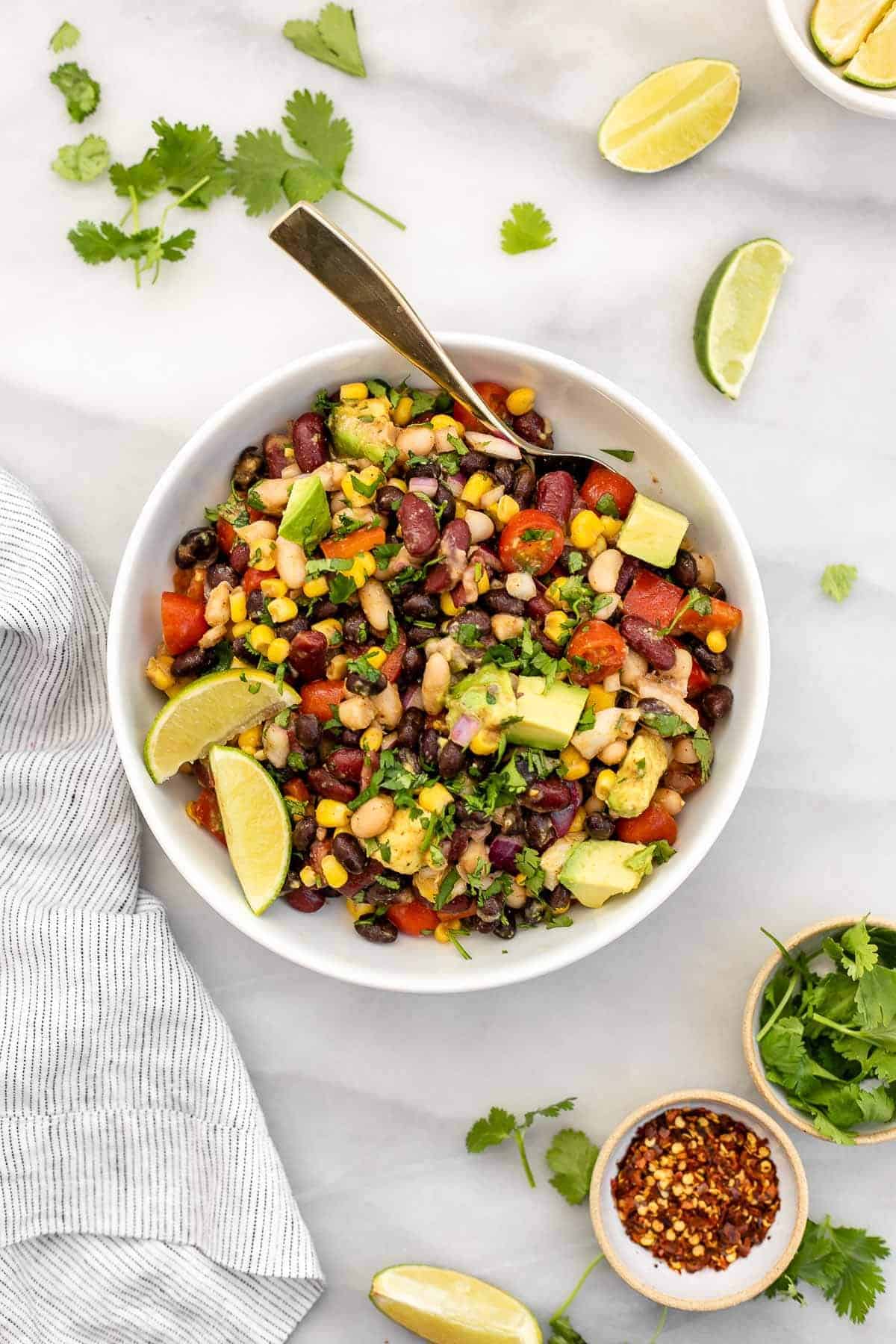 mexican three bean salad in a bowl with lime and avocado