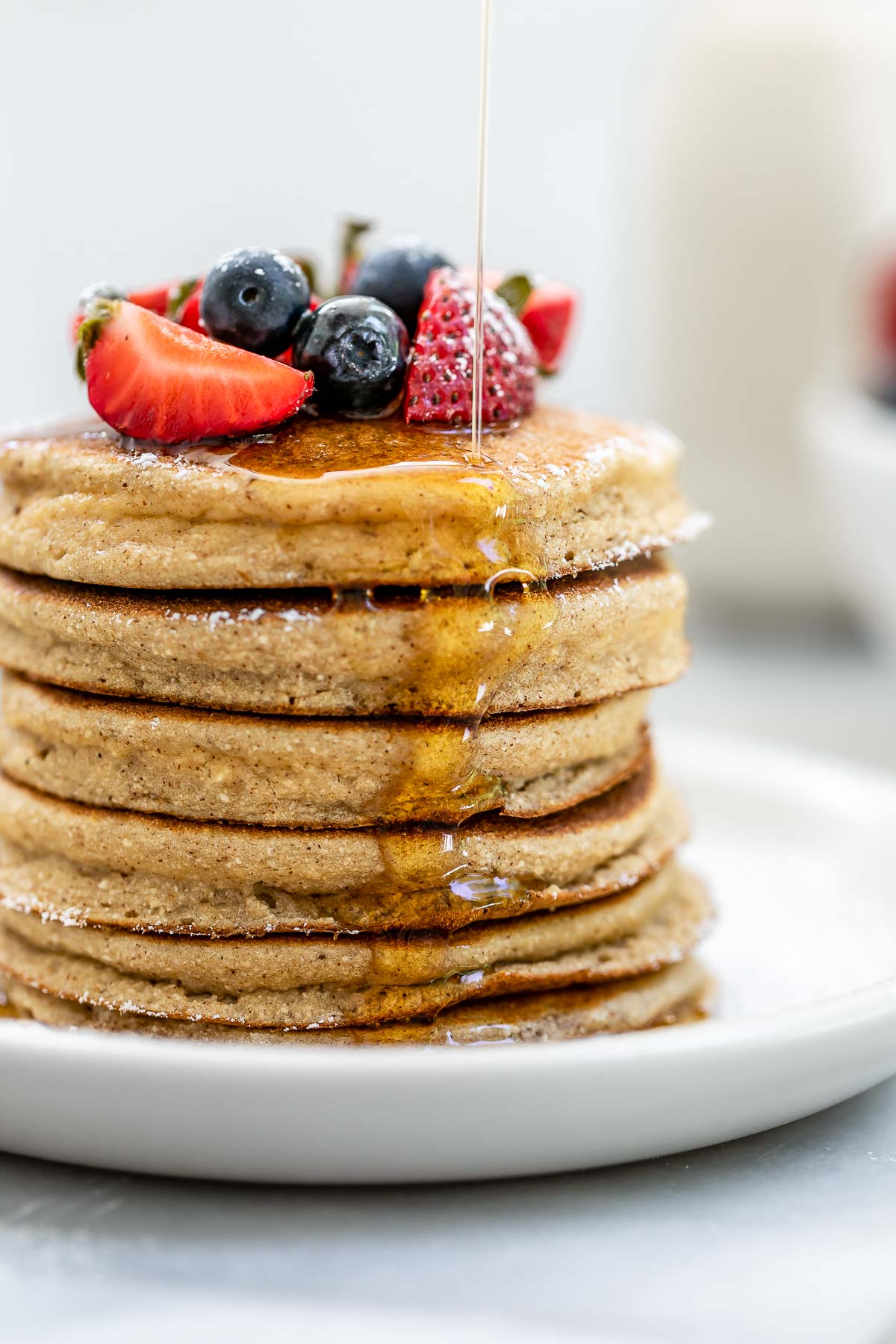Up close image of the coconut flour pancakes with maple syrup dripping down.