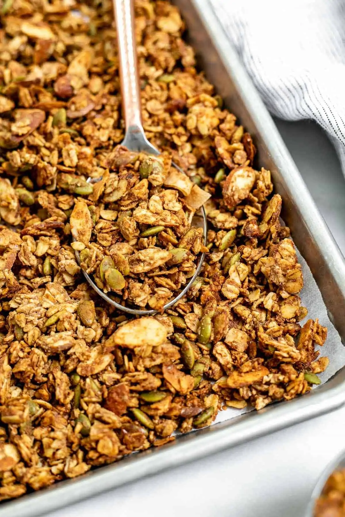 Up close image of the final gluten free granola on a baking tray with a spoon.
