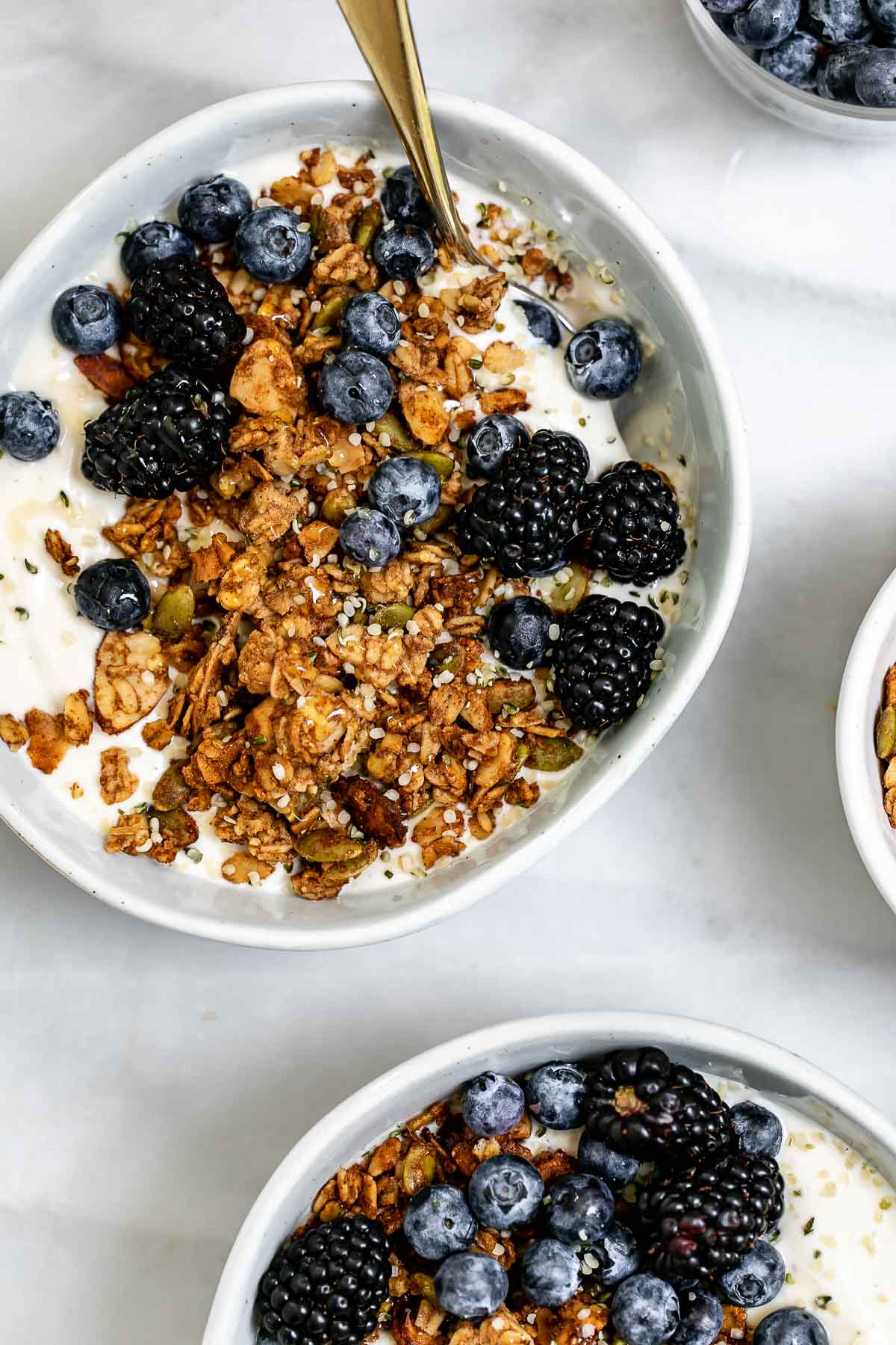 Two bowls with yogurt, granola and berries.