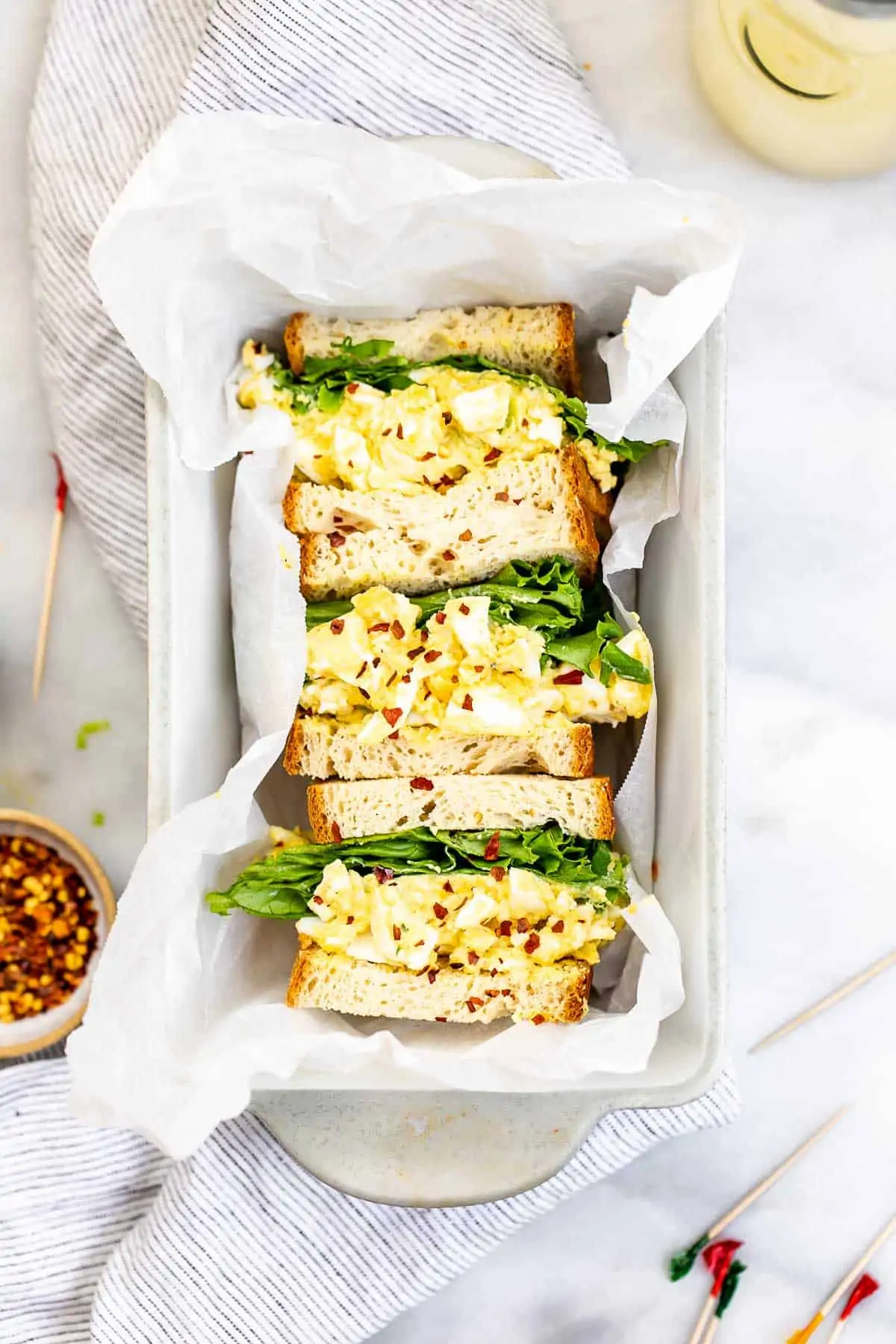 Egg salad sandwiches in a bread pan with parchment paper. 