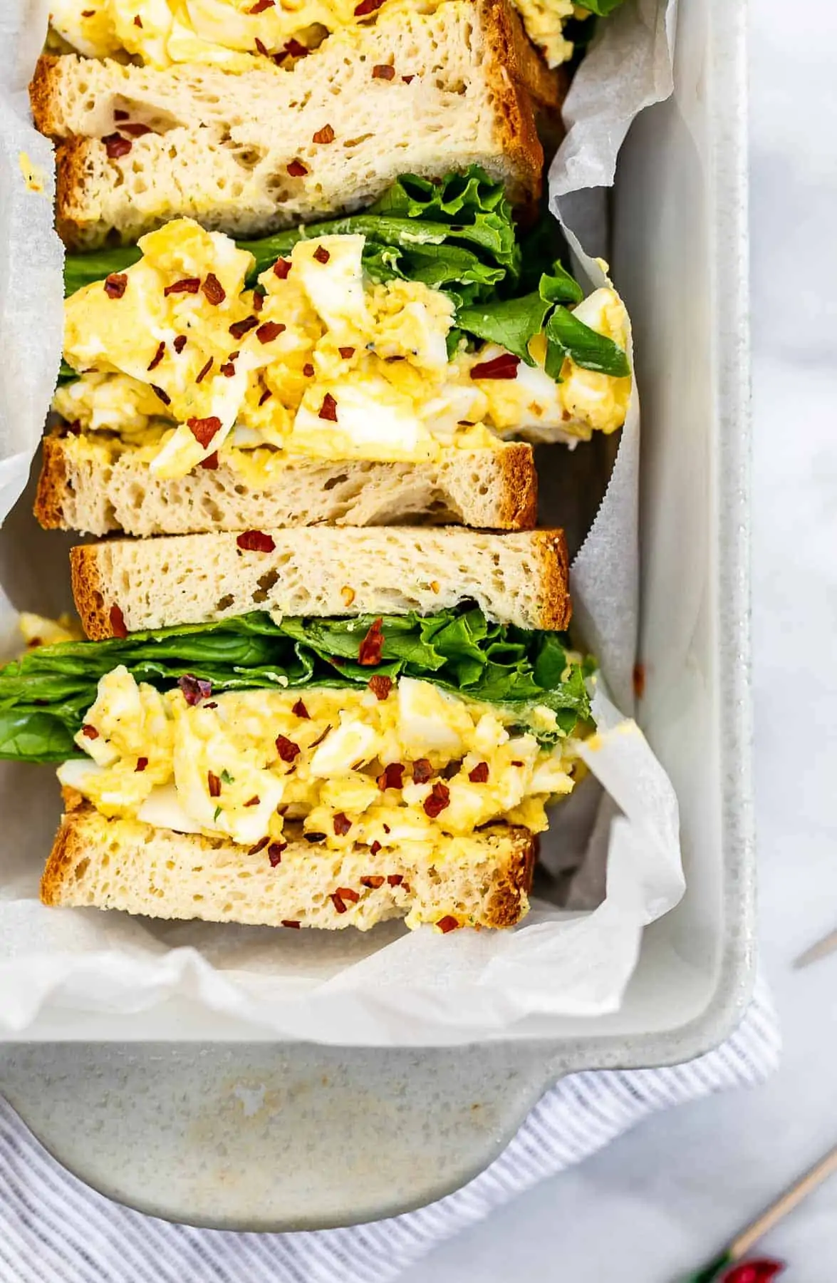 Up close image of the egg salad sandwich with red pepper flakes. 