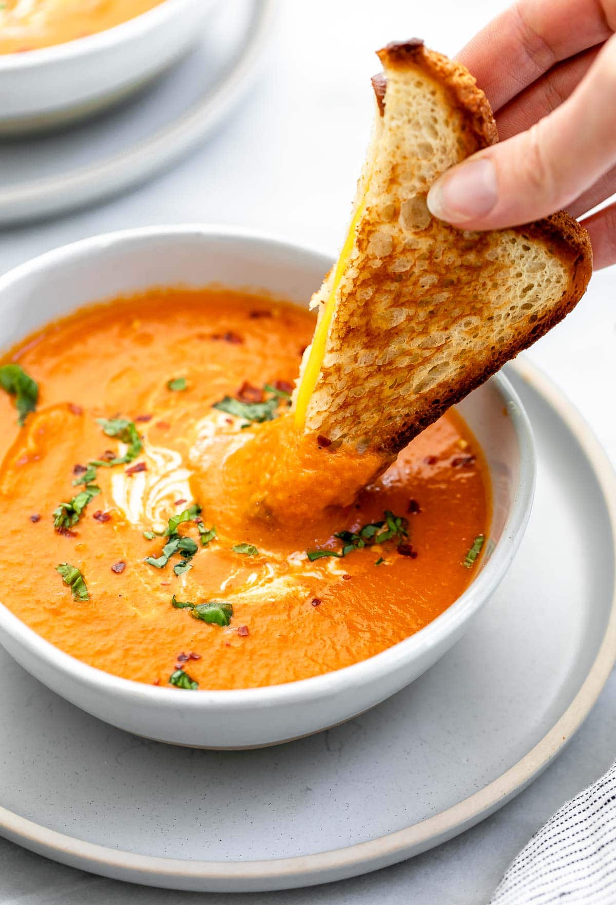 Dipping a grilled cheese into a bowl of the tomato soup.