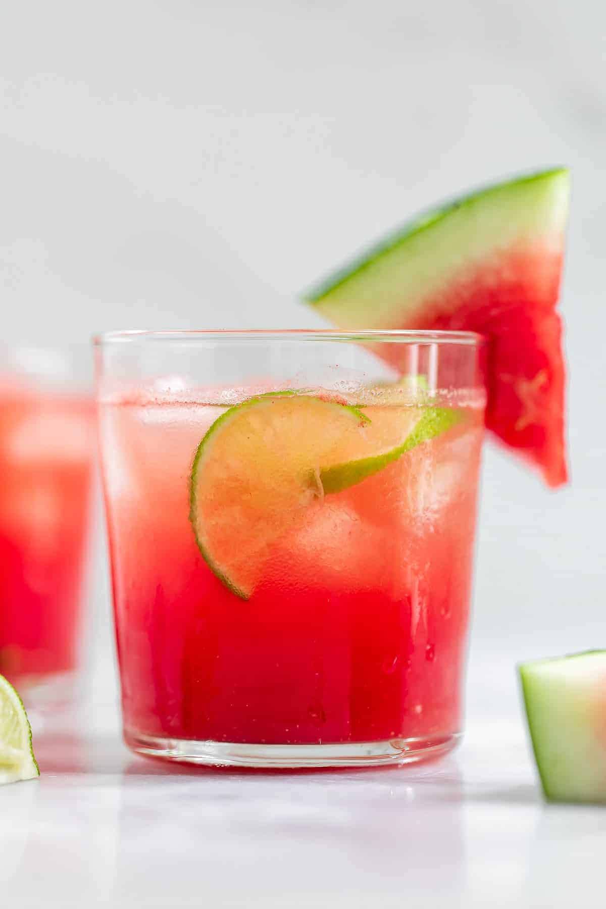 Up close image of the vodka cocktail with lime and watermelon wedges.