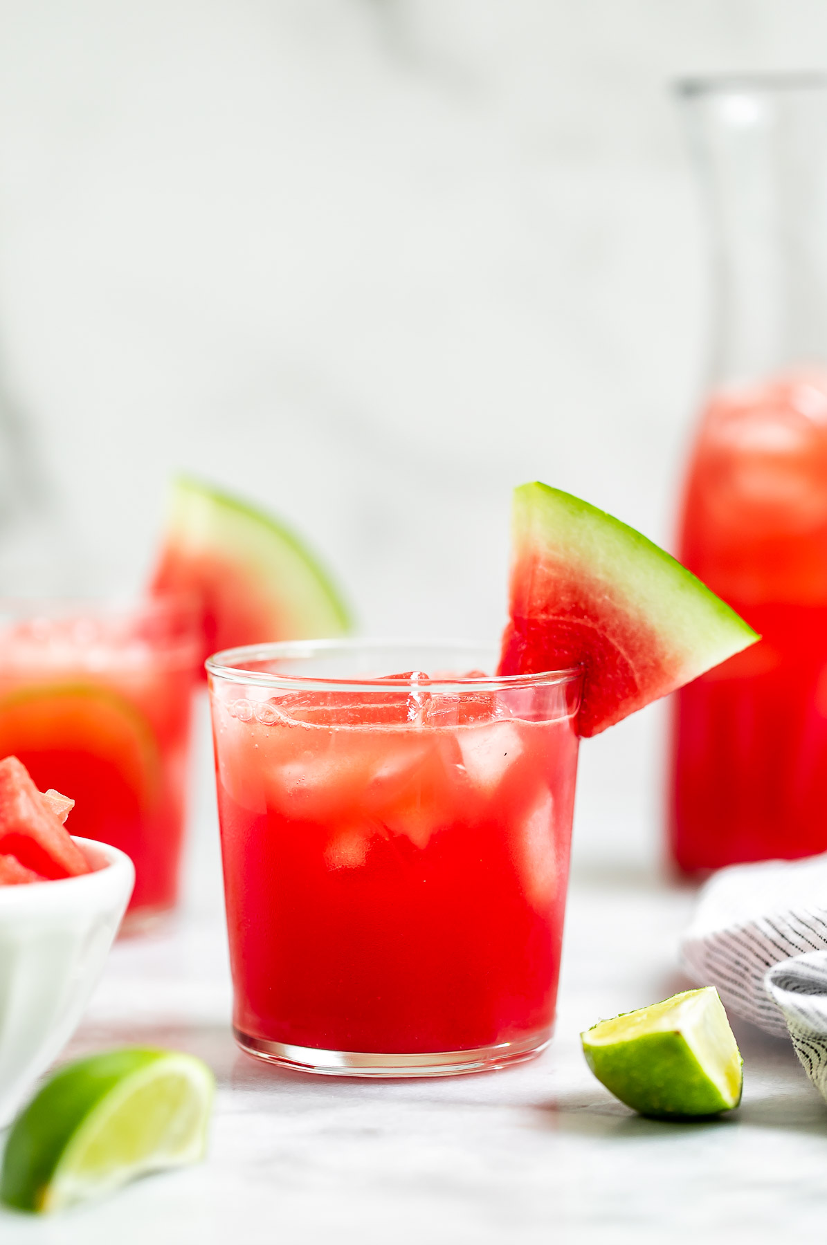 Vodka Cocktail in a glass with ice and watermelon wedges on the side.