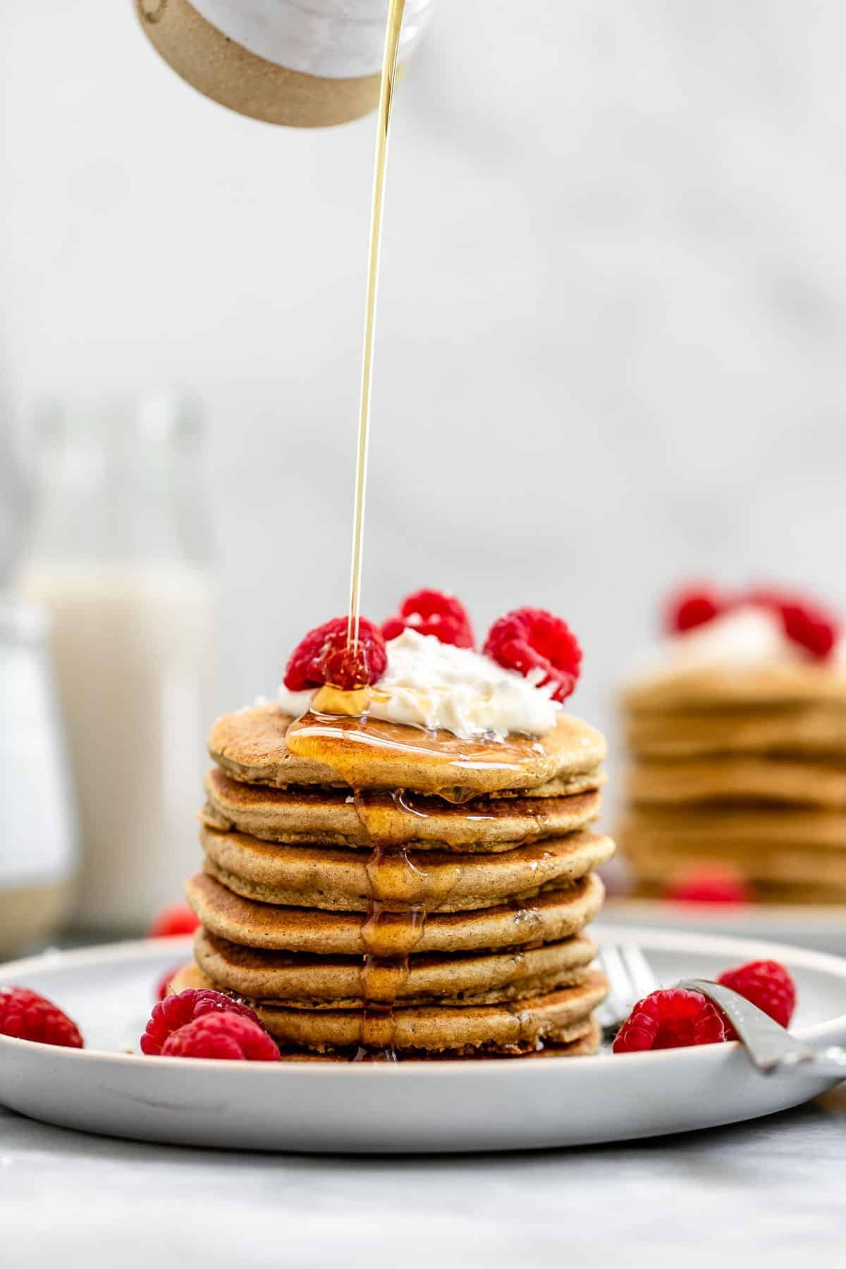 two stacks of vegan pancakes with raspberries on top