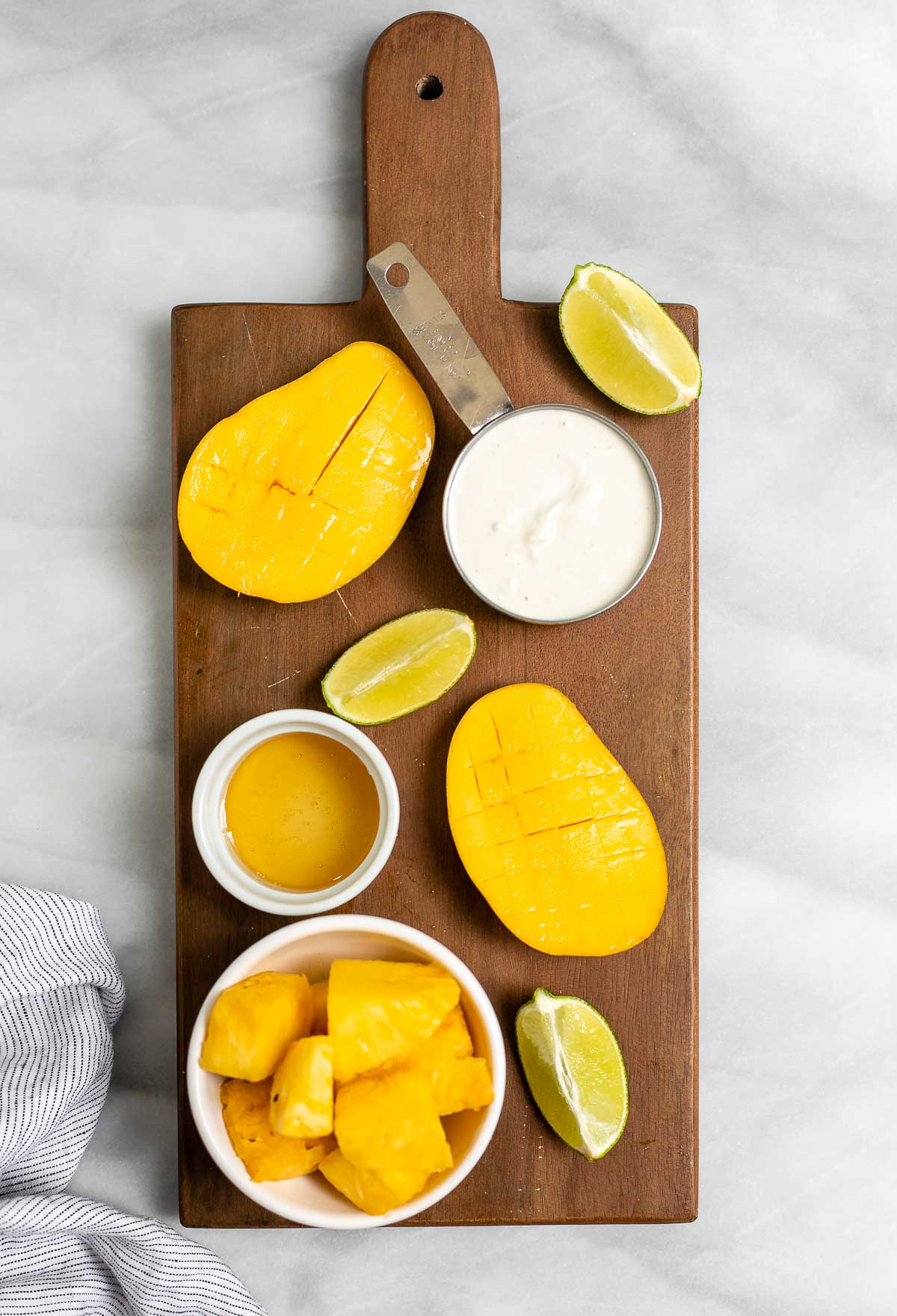 Ingredients for the mango popsicles on a wood board.