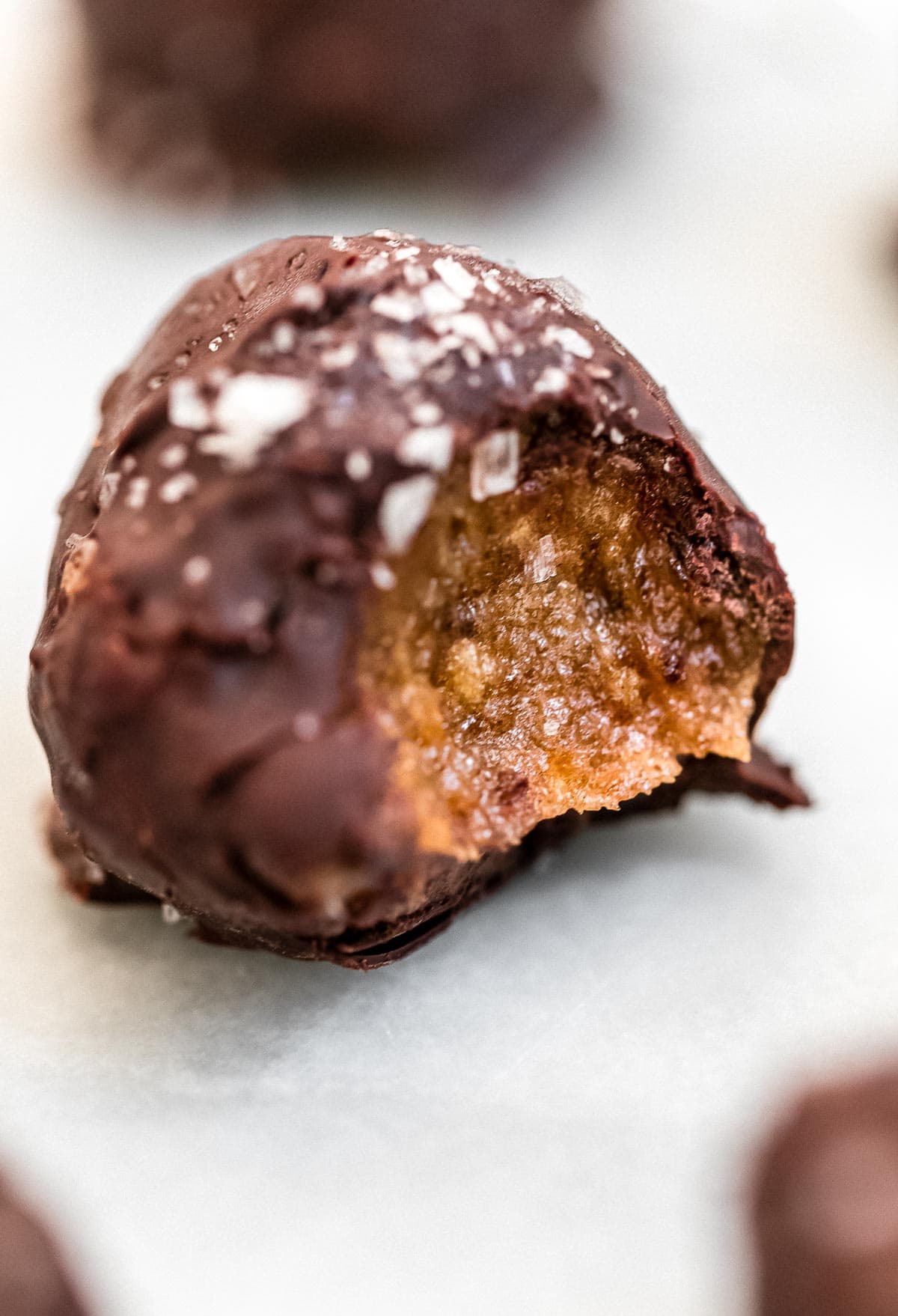 Up close image of one vegan truffle with a bite taken out.