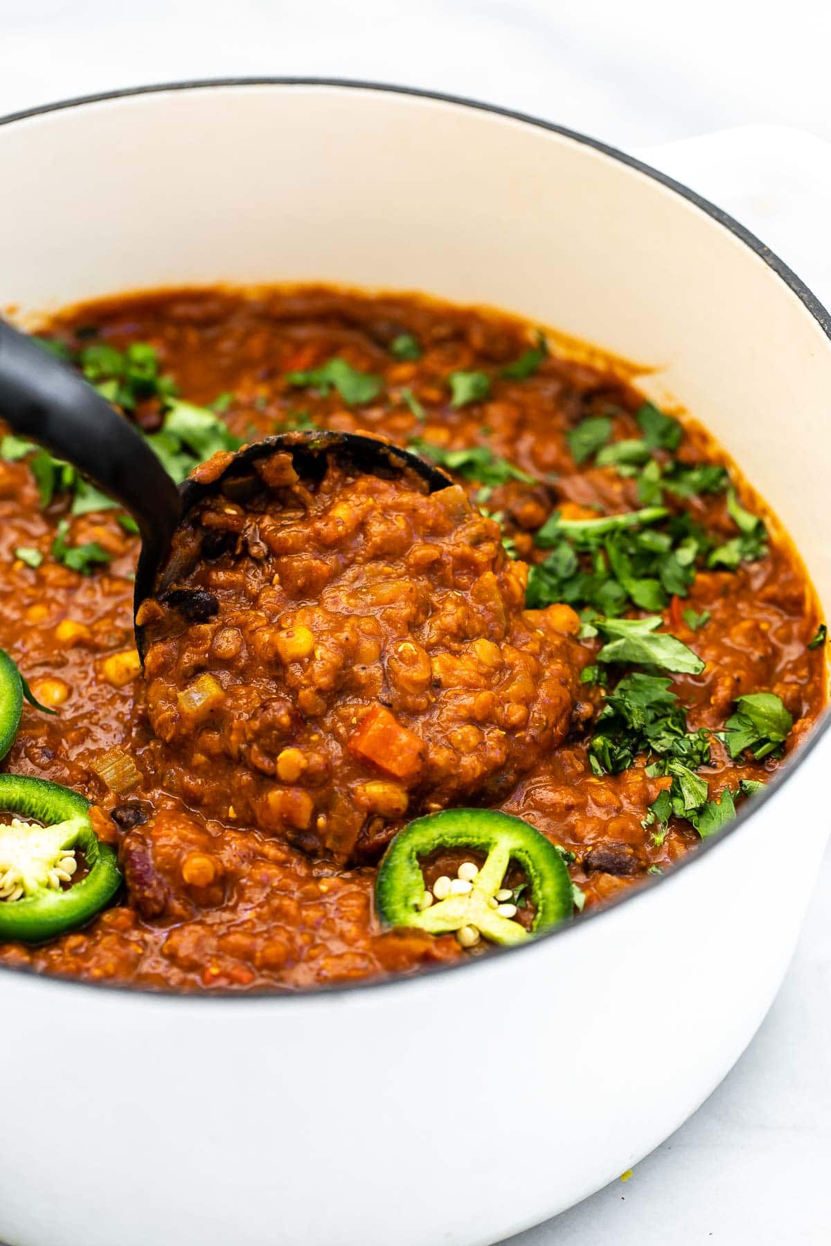 Lentil chili in a large white pot with a ladle. 