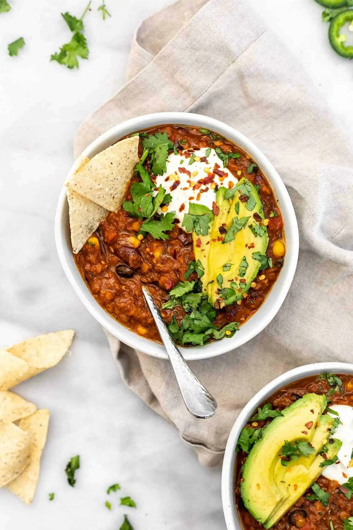 Vegan lentil chili in a bowl with sour cream and avocado. 