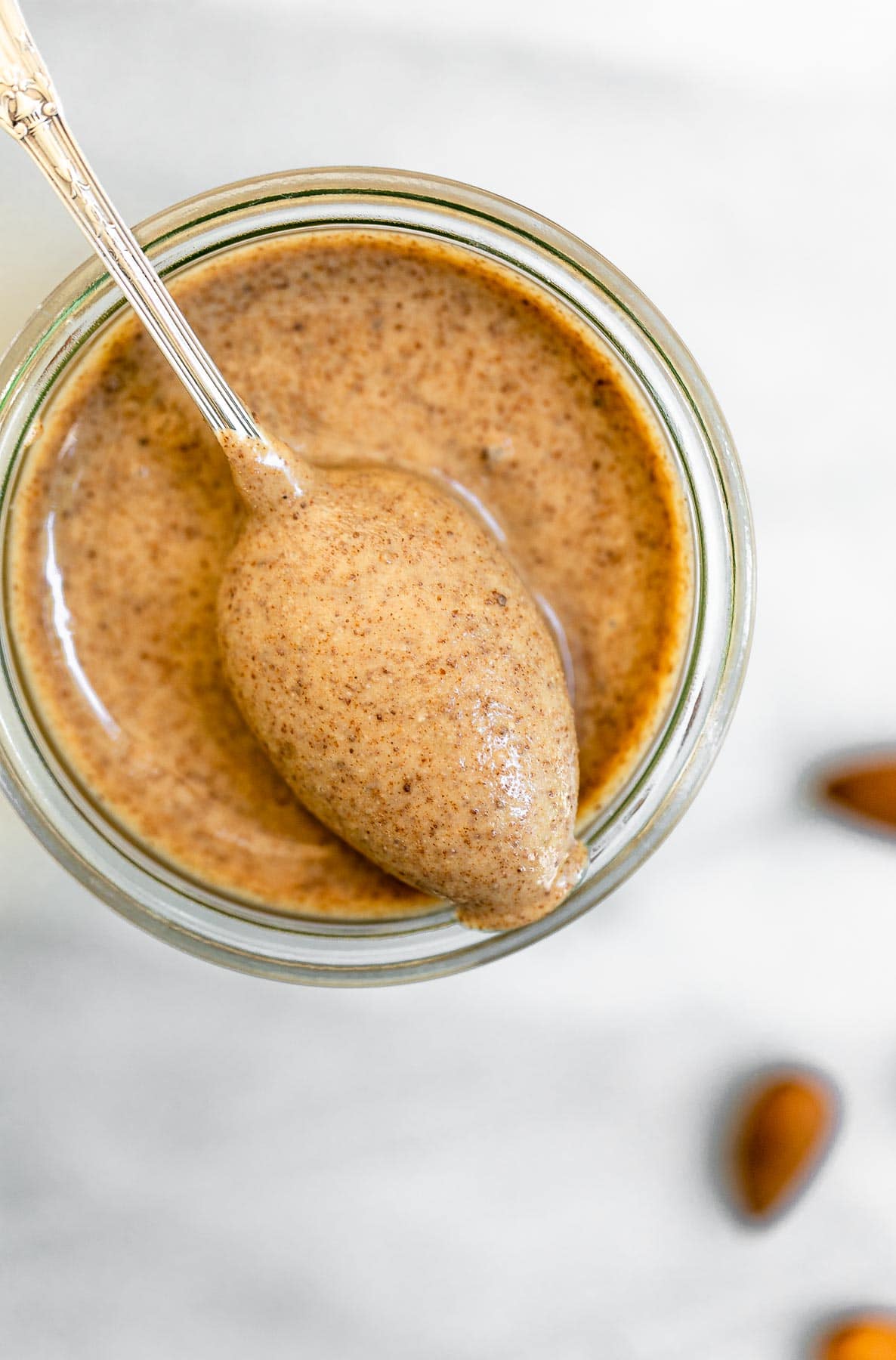 Homemade almond butter in a jar with a spoon on top.