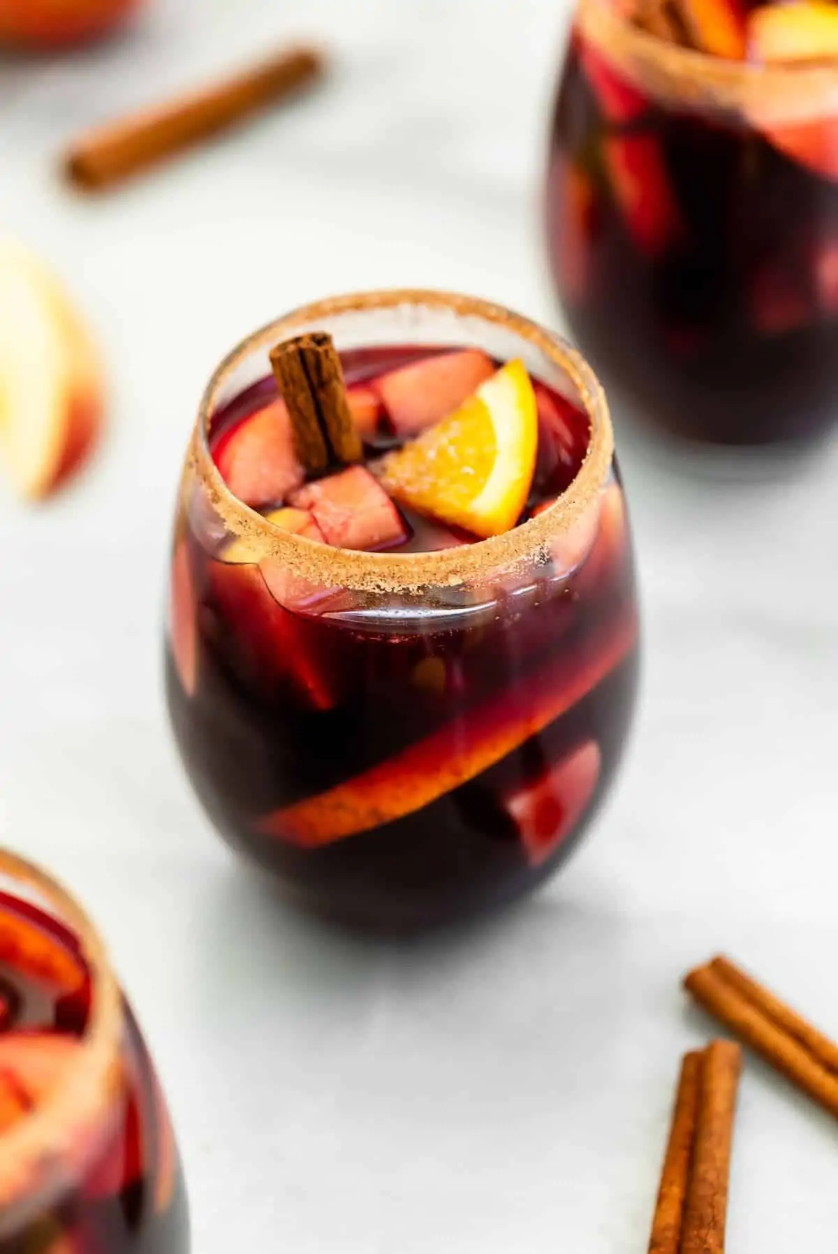 Apple cider red wine sangria with a cinnamon sugar rim in a stemless wine glass.