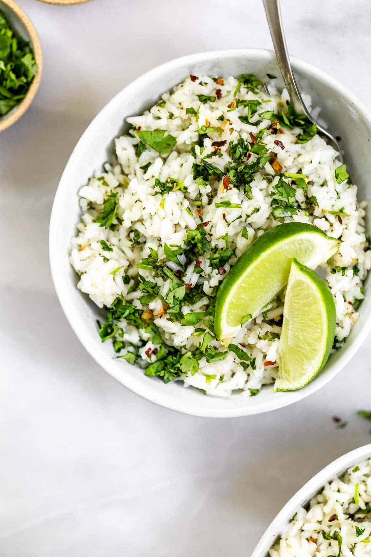 CIlantro lime rice in a small blue bowl with lime wedges.