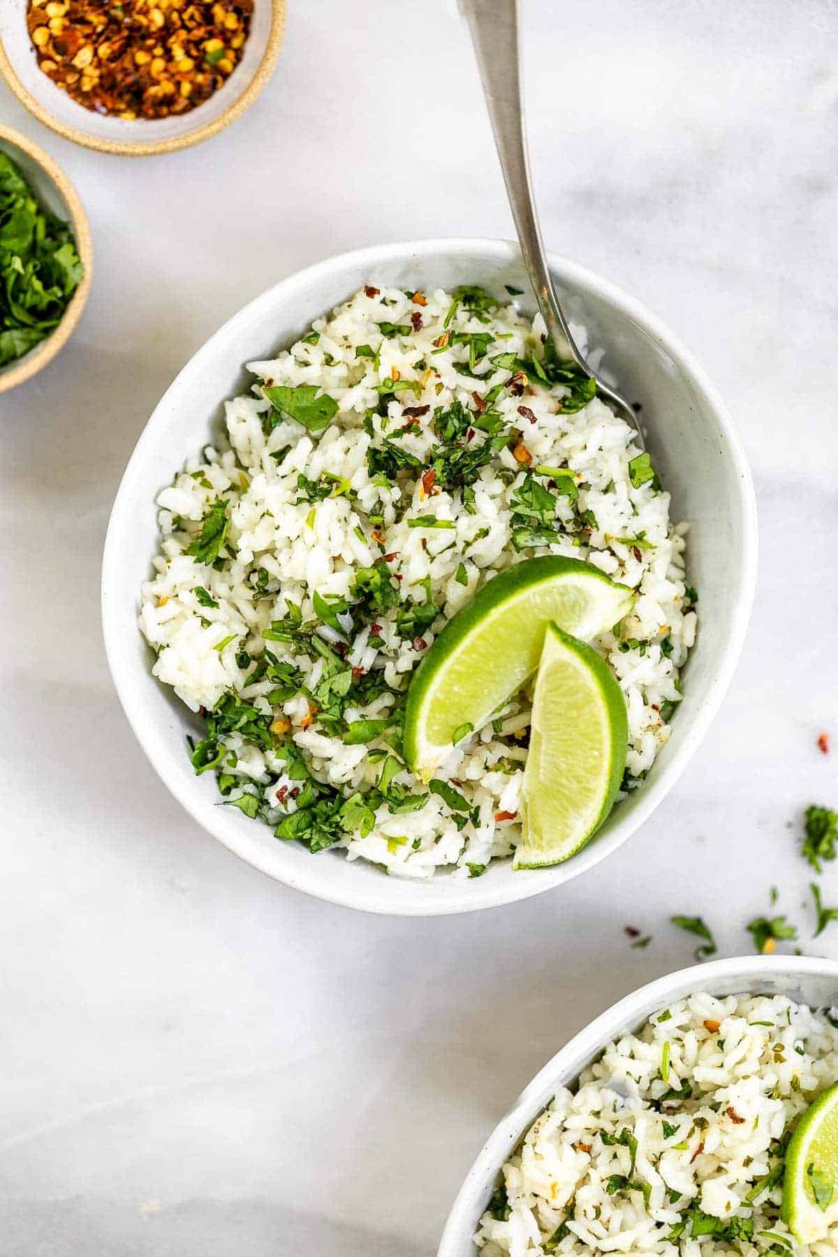 Two bowls of cilantro lime rice with lime wedges on top.