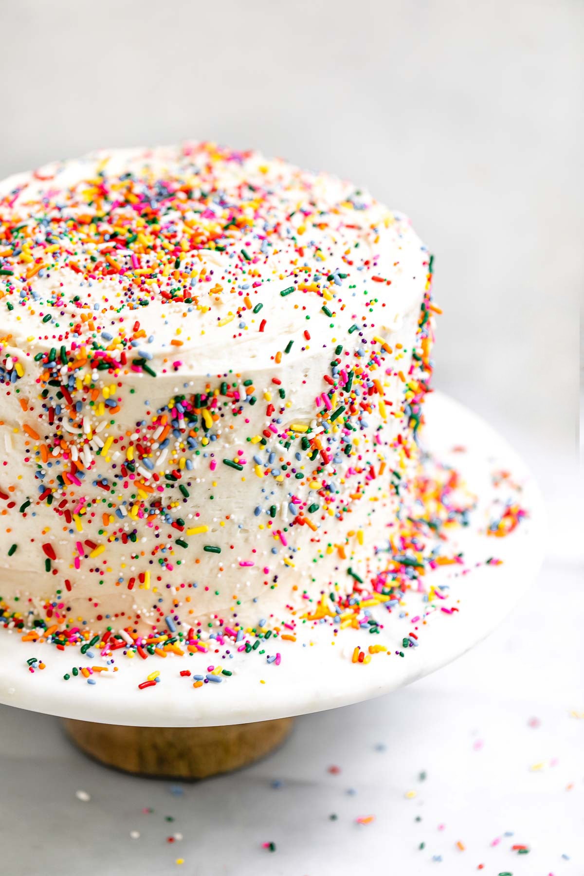 vegan gluten free vanilla cake with sprinkles on a cake stand