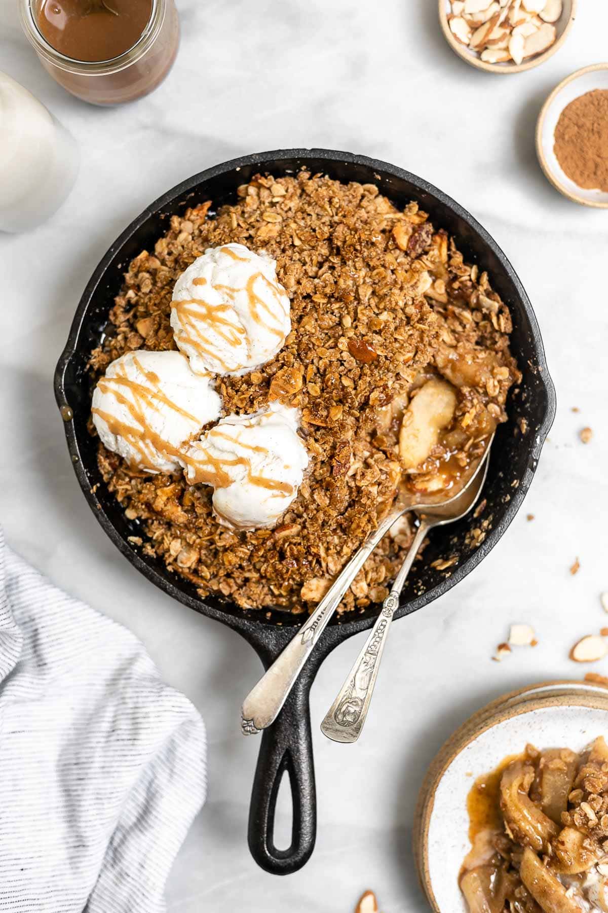 Final recipe in a skillet with two spoons and ice cream on the side.