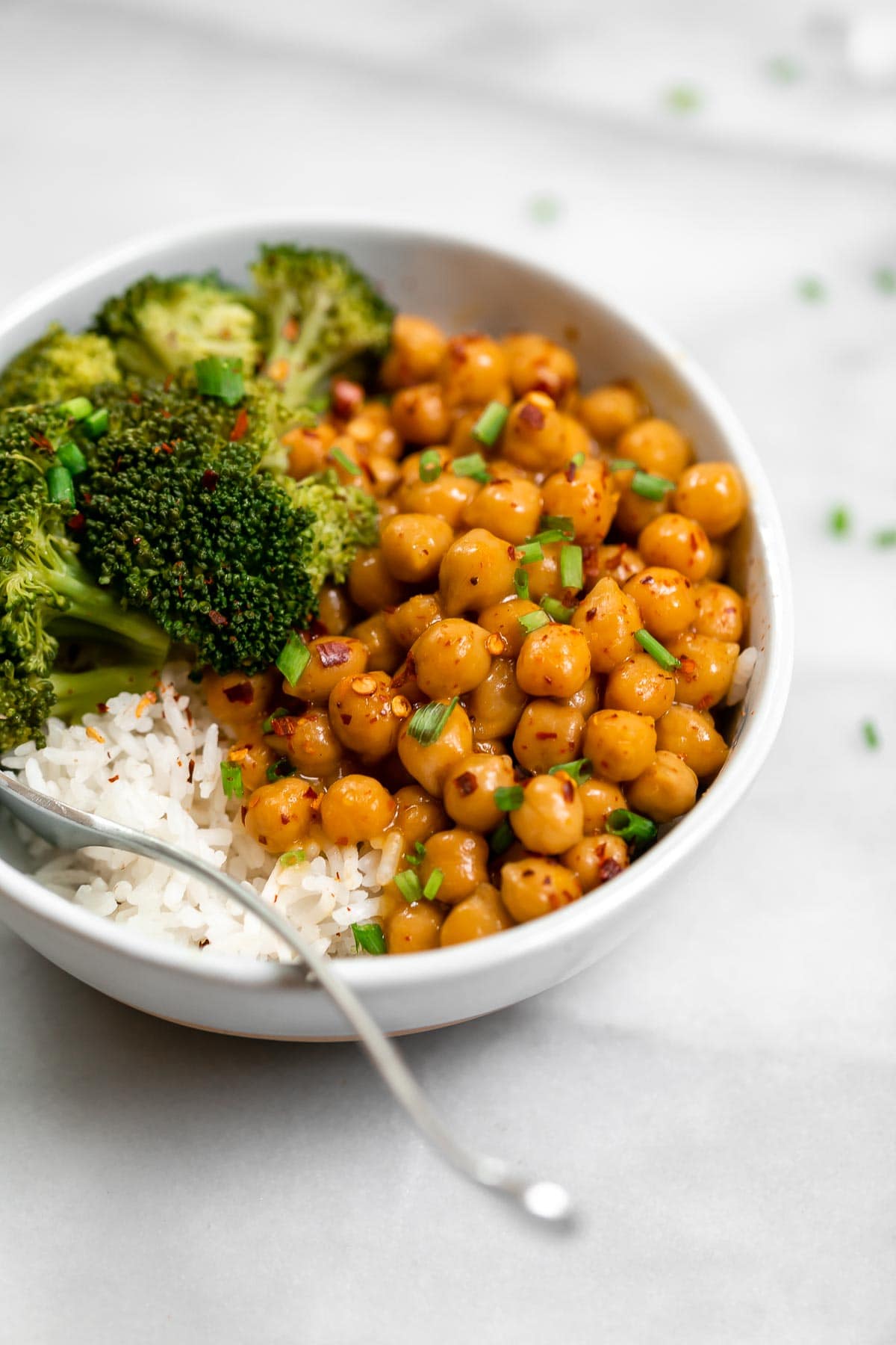 Angled view of the final orange chickpeas with broccoli in a buddha bowl.
