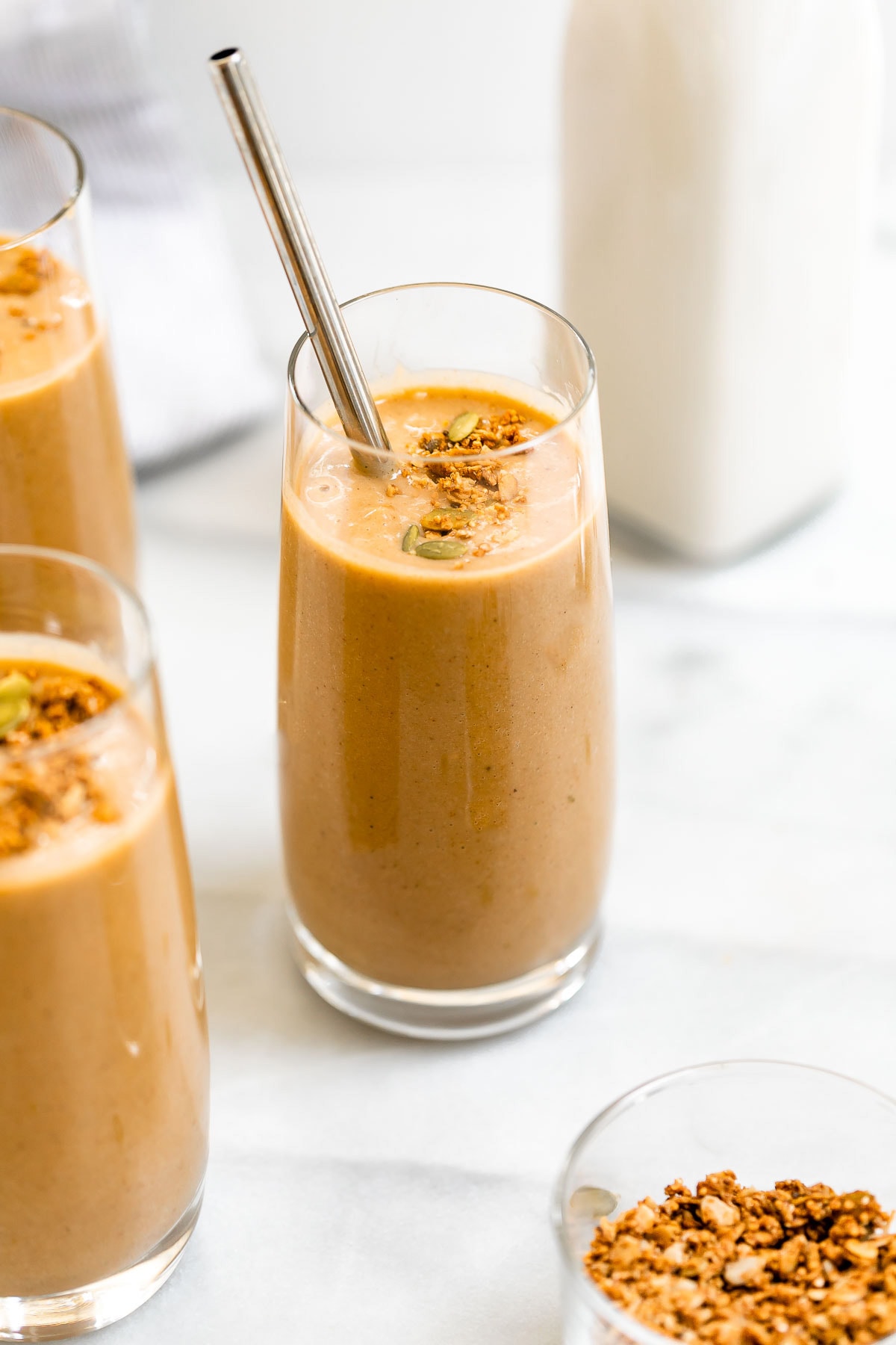 Two healthy smoothies in glass cups with granola on top. 