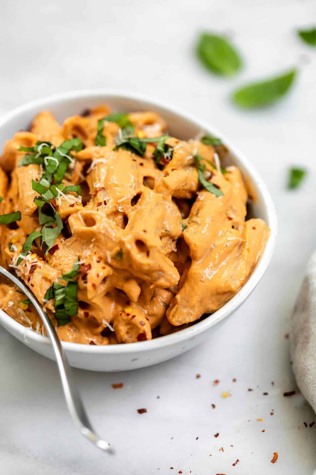 Tahini penne in a bowl with basil on top.